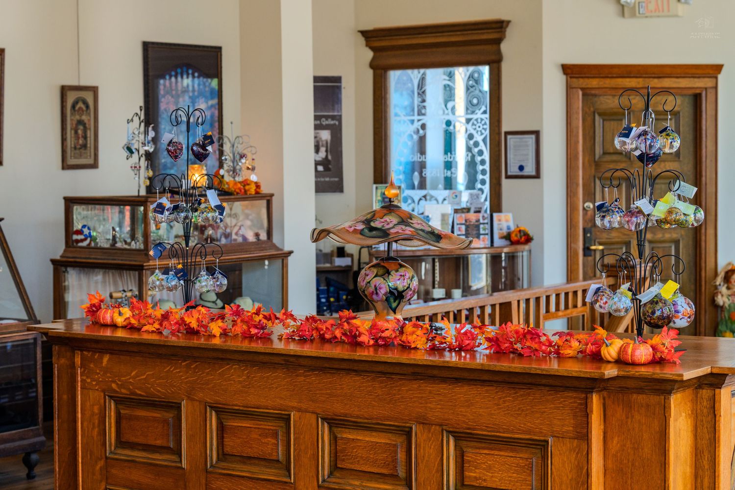 Elegant wooden reception counter adorned with autumn floral garland and decorative gift shop displays.