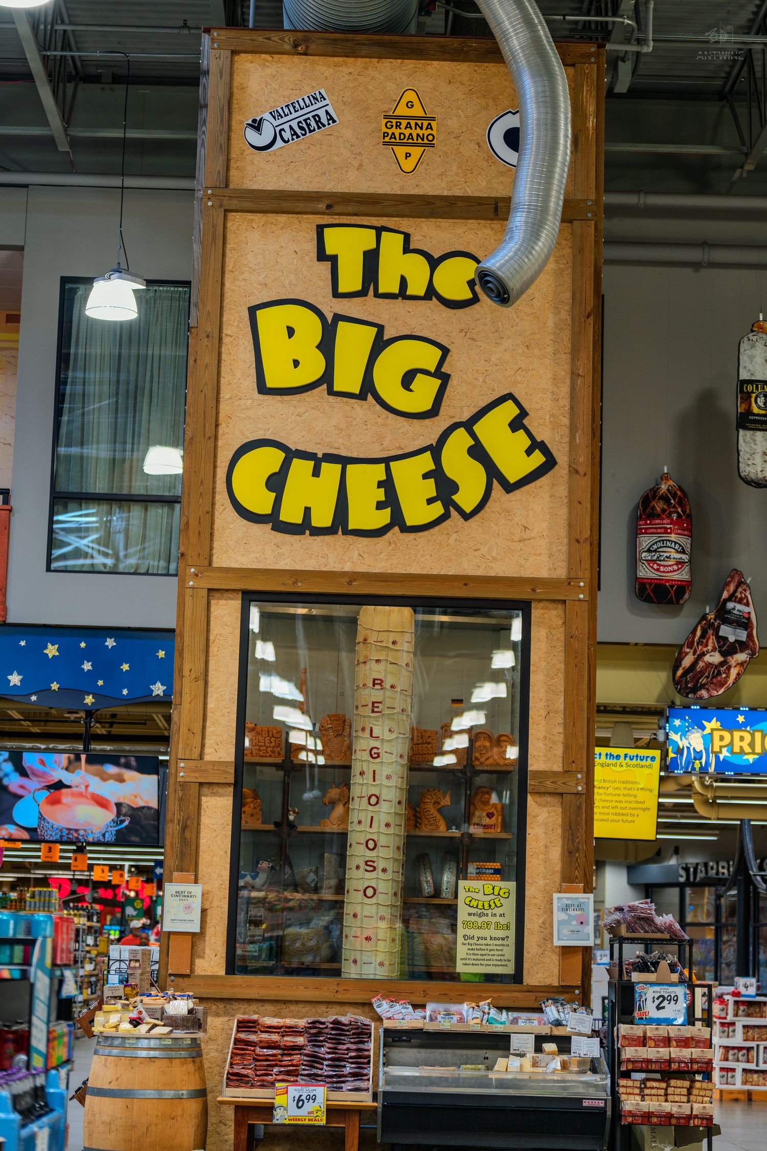 The Big Cheese refrigerated display case in a grocery store deli section featuring specialty cheeses.