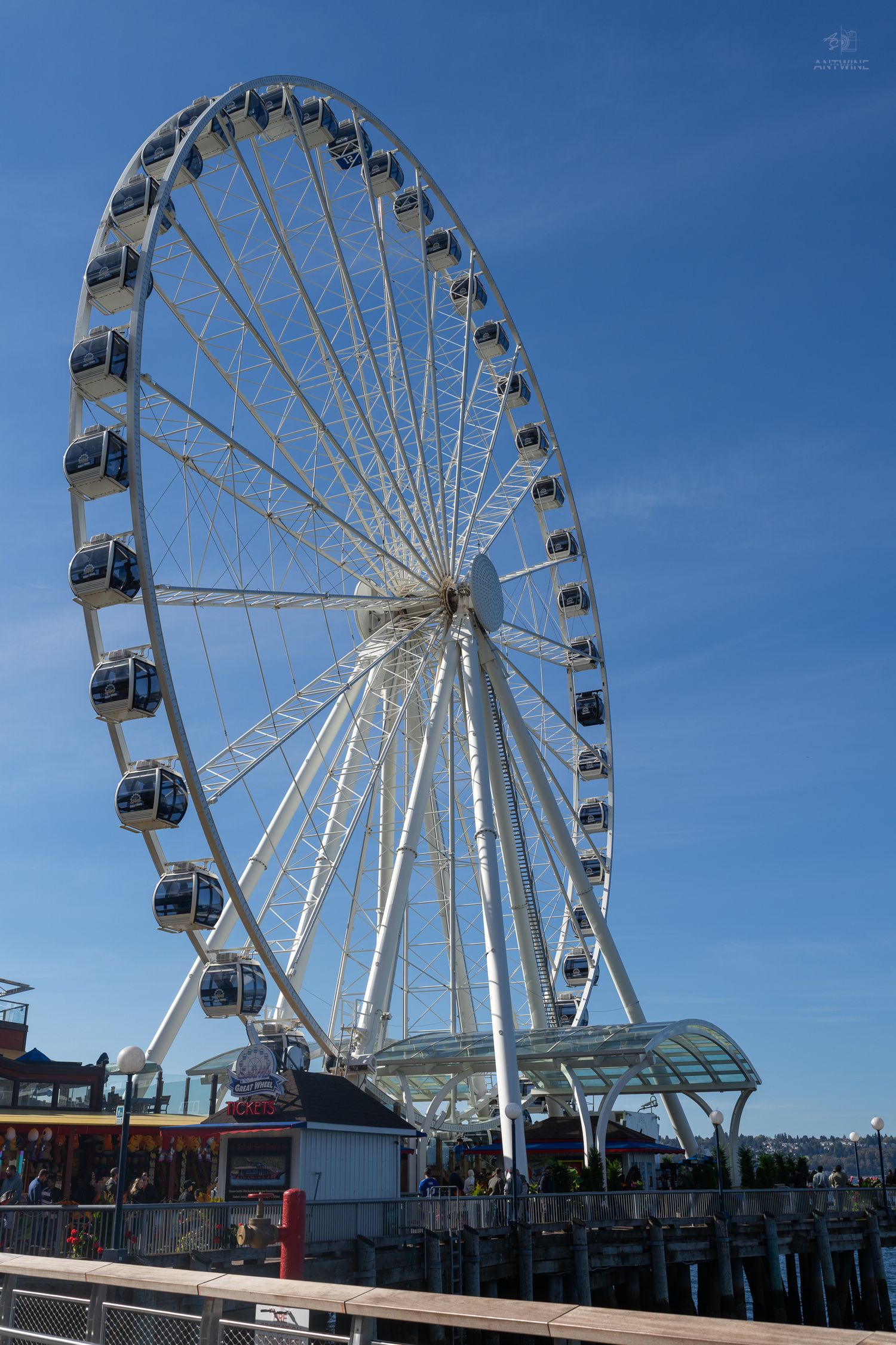 Seattle Great Wheel ferris wheel standing tall against blue sky on the waterfront pier on a sunny day.