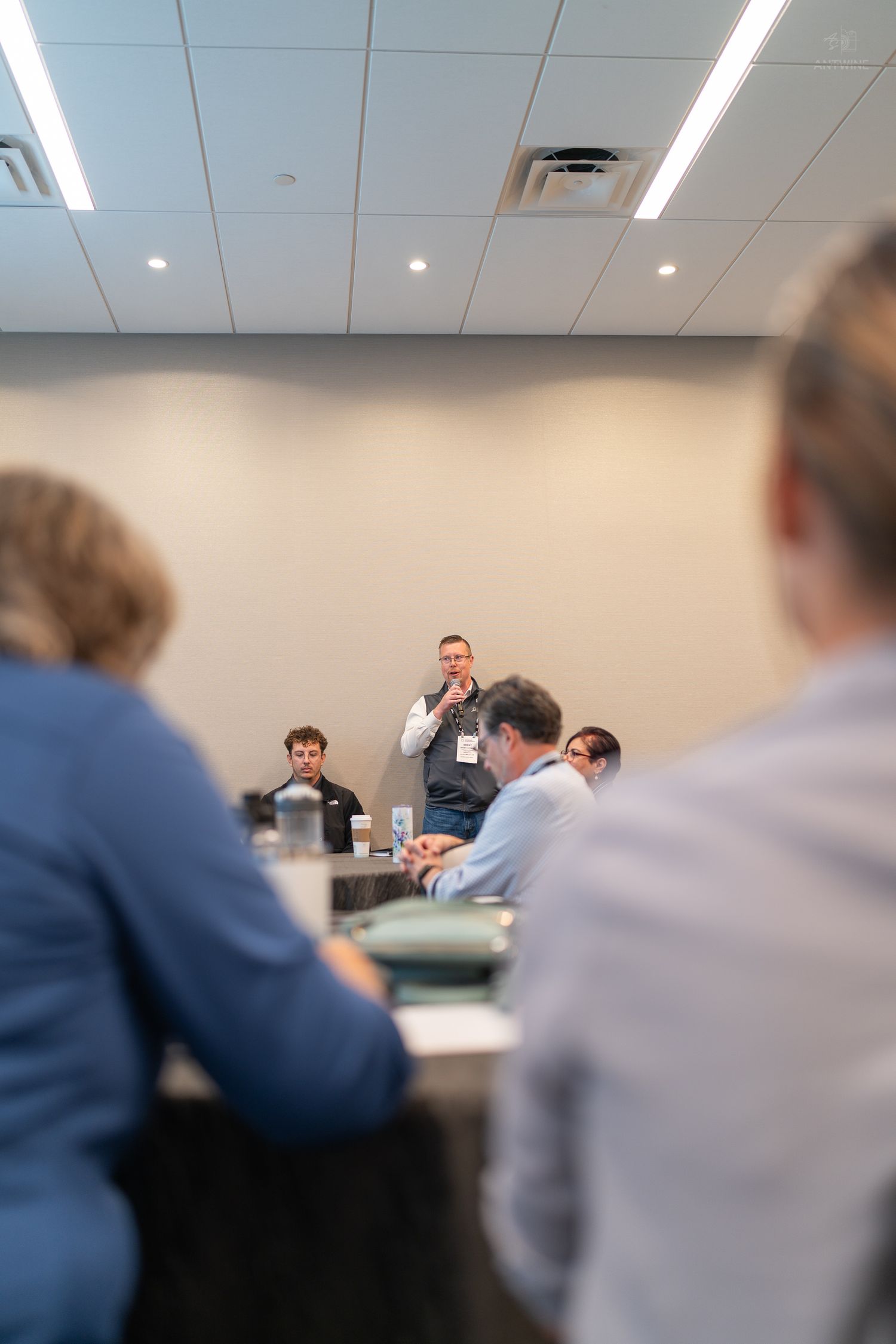A speaker addresses a small group at a conference room panel discussion.