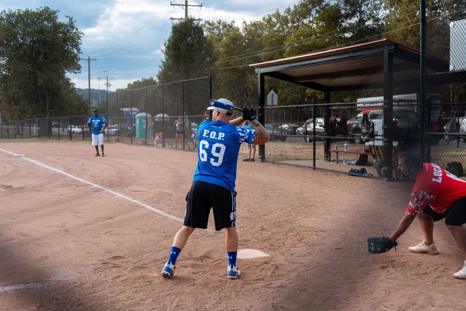 A batter wearing jersey number 69 prepares to swing at a softball during an outdoor game.