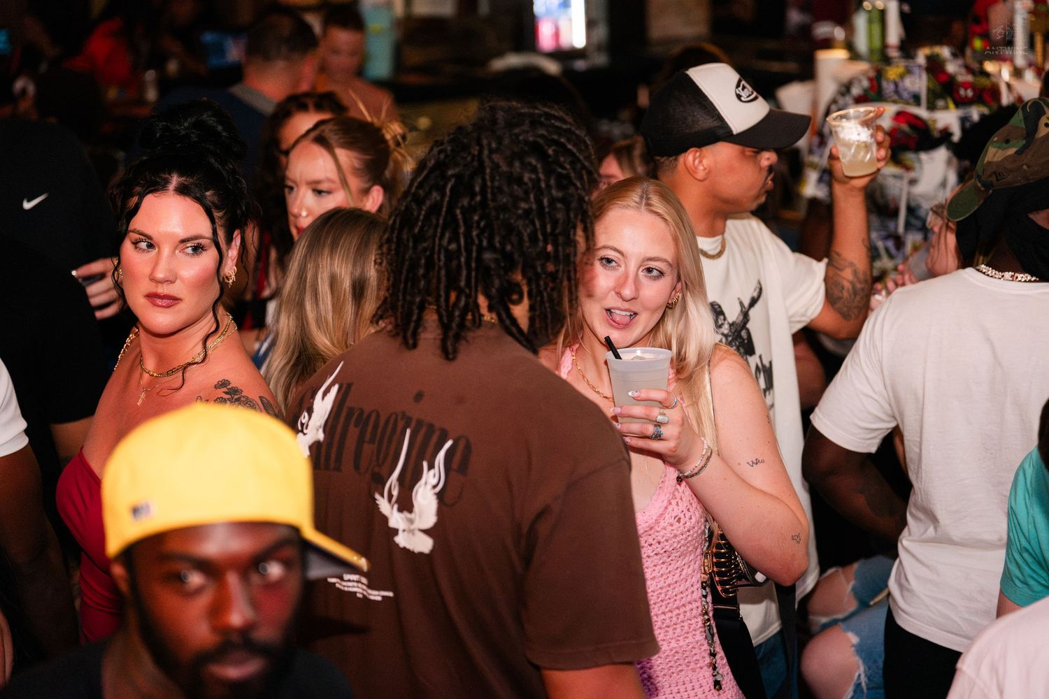 Diverse group of young adults enjoying drinks at a vibrant indoor party.