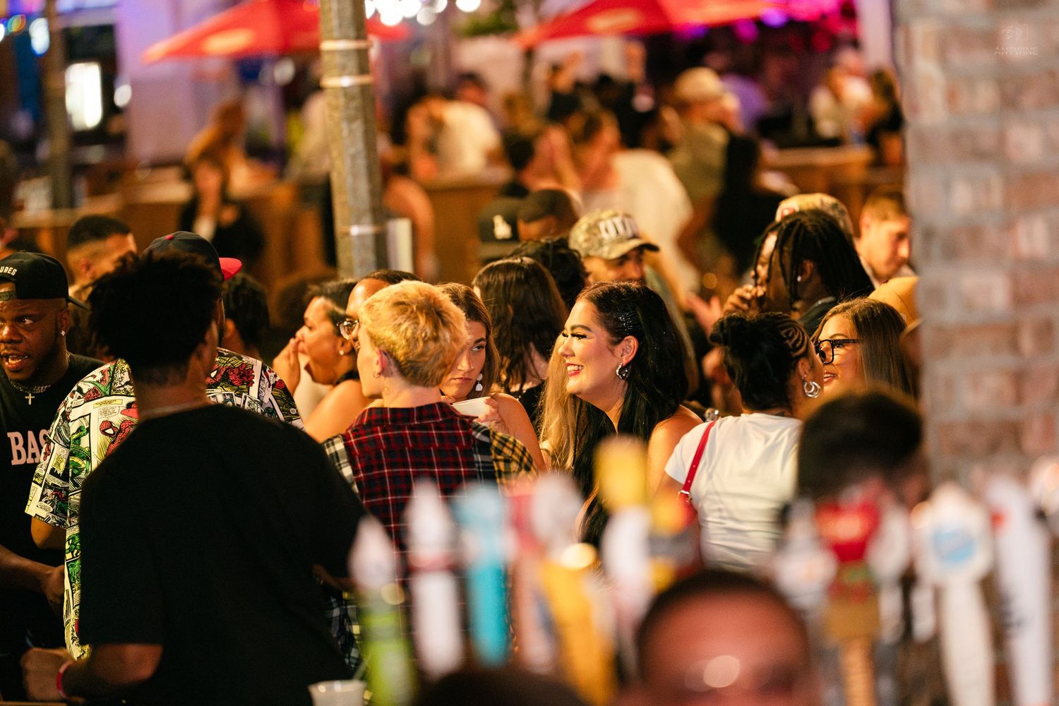 Diverse crowd socializing at a busy outdoor bar at night.