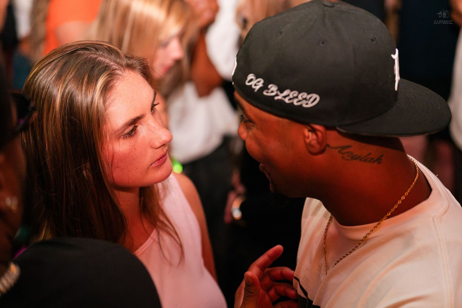 A woman and a man in a cap engage in close conversation at a crowded event.