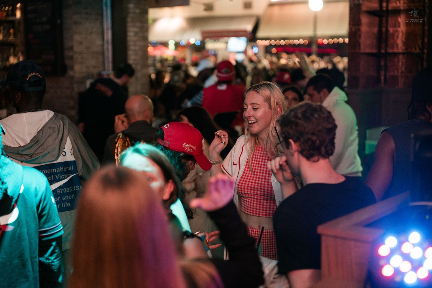 Blonde woman in red top dancing and smiling at an energetic nightclub party.