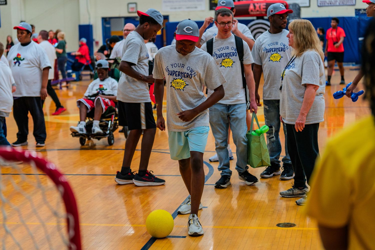 Special Olympics indoor bocce ball event with participants and volunteers on a gymnasium court.