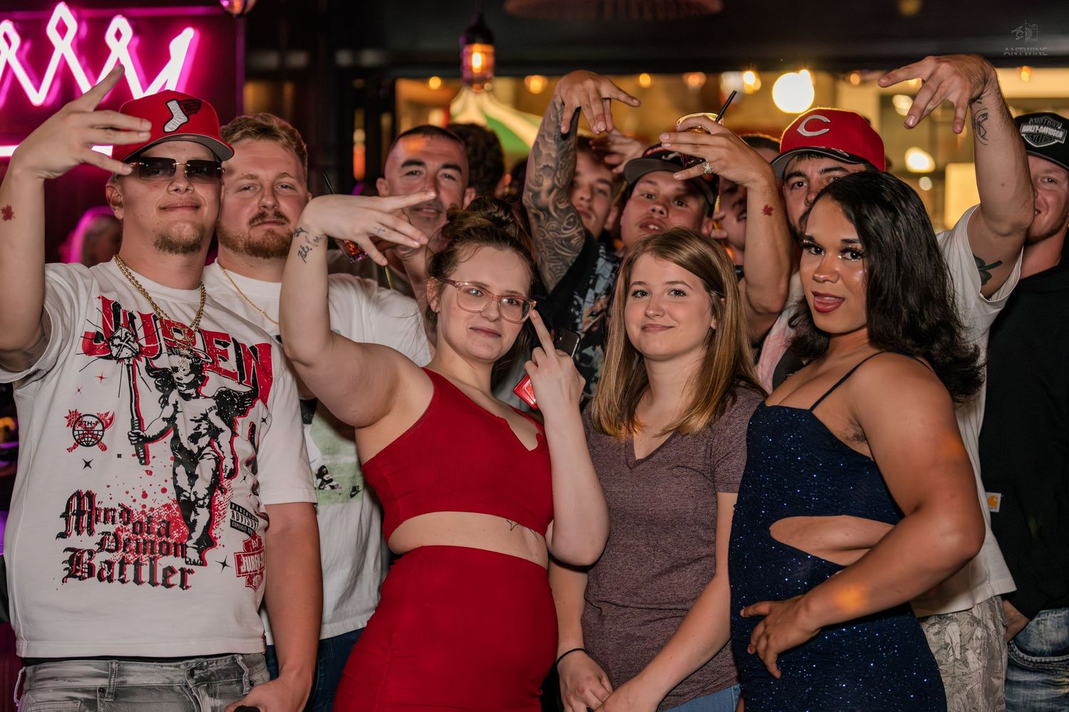 Large group of friends posing and taking selfies at a lively bar event.