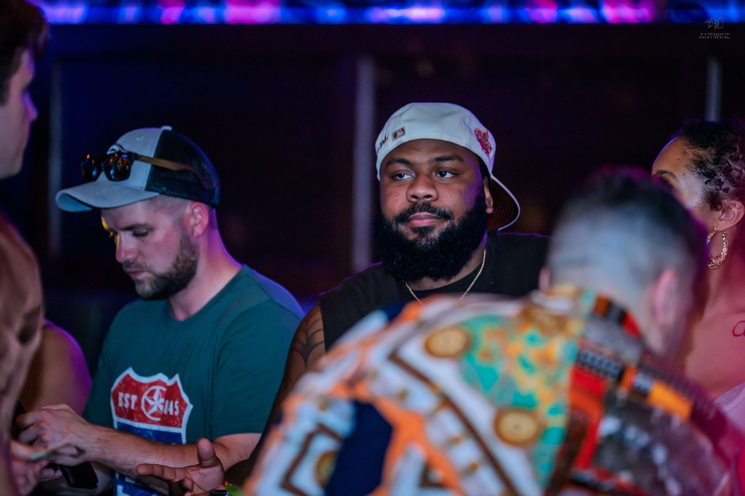 Group of people at a boxing event with a championship belt visible in the background.