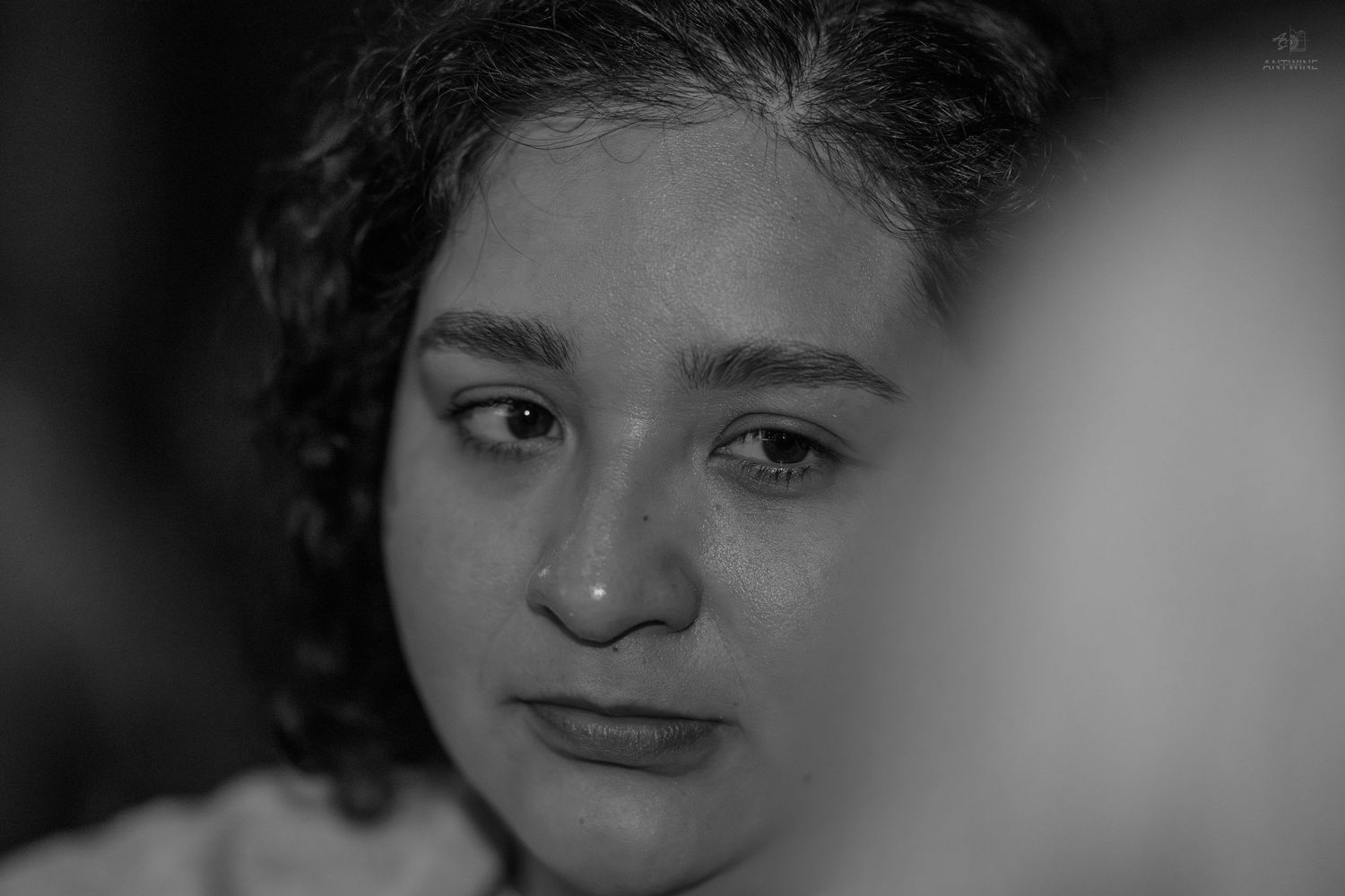 Black and white close-up portrait of a young girl with curly hair and expressive eyes.