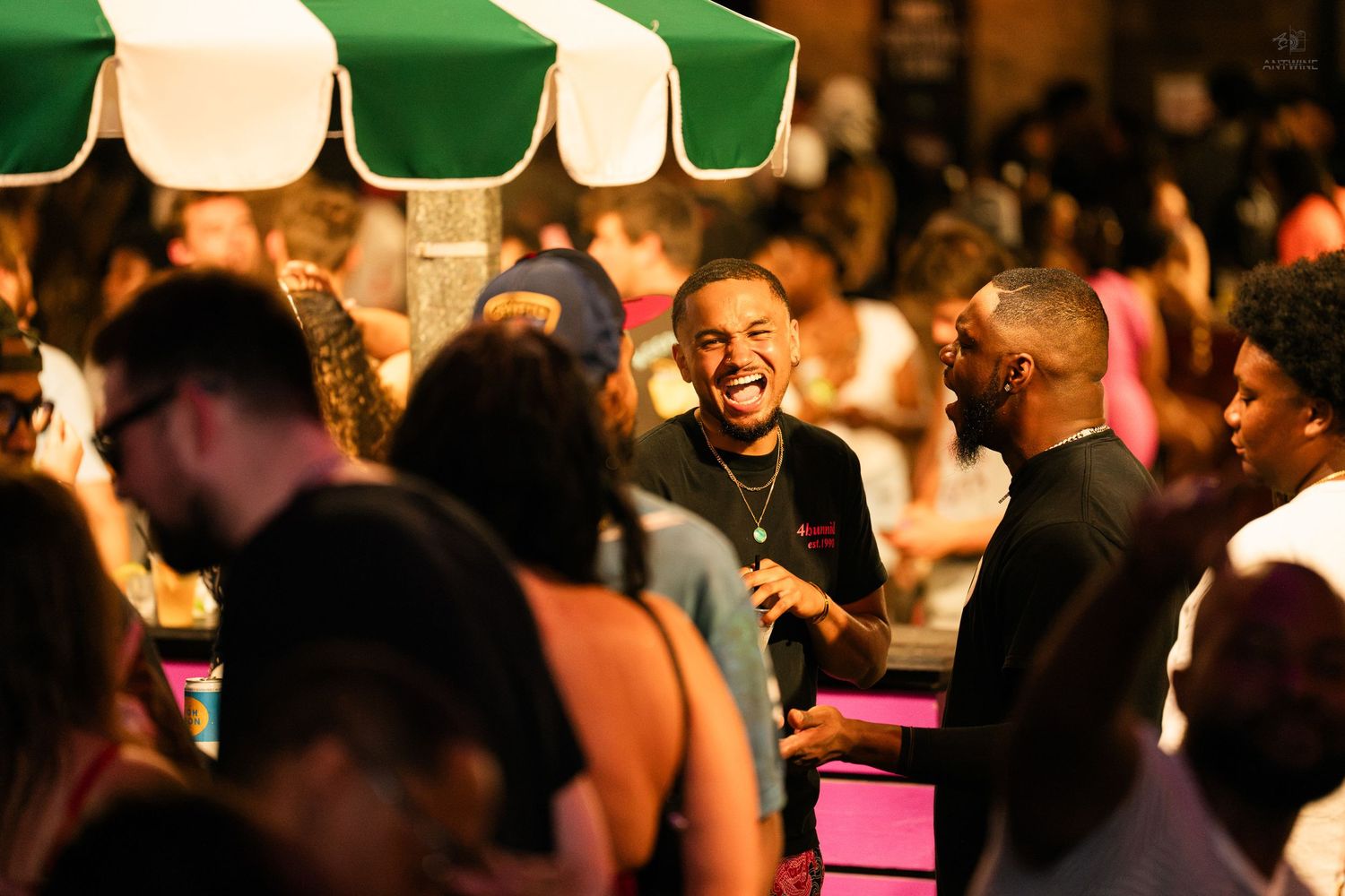 Group of people socializing and laughing outdoors at a lively evening event.