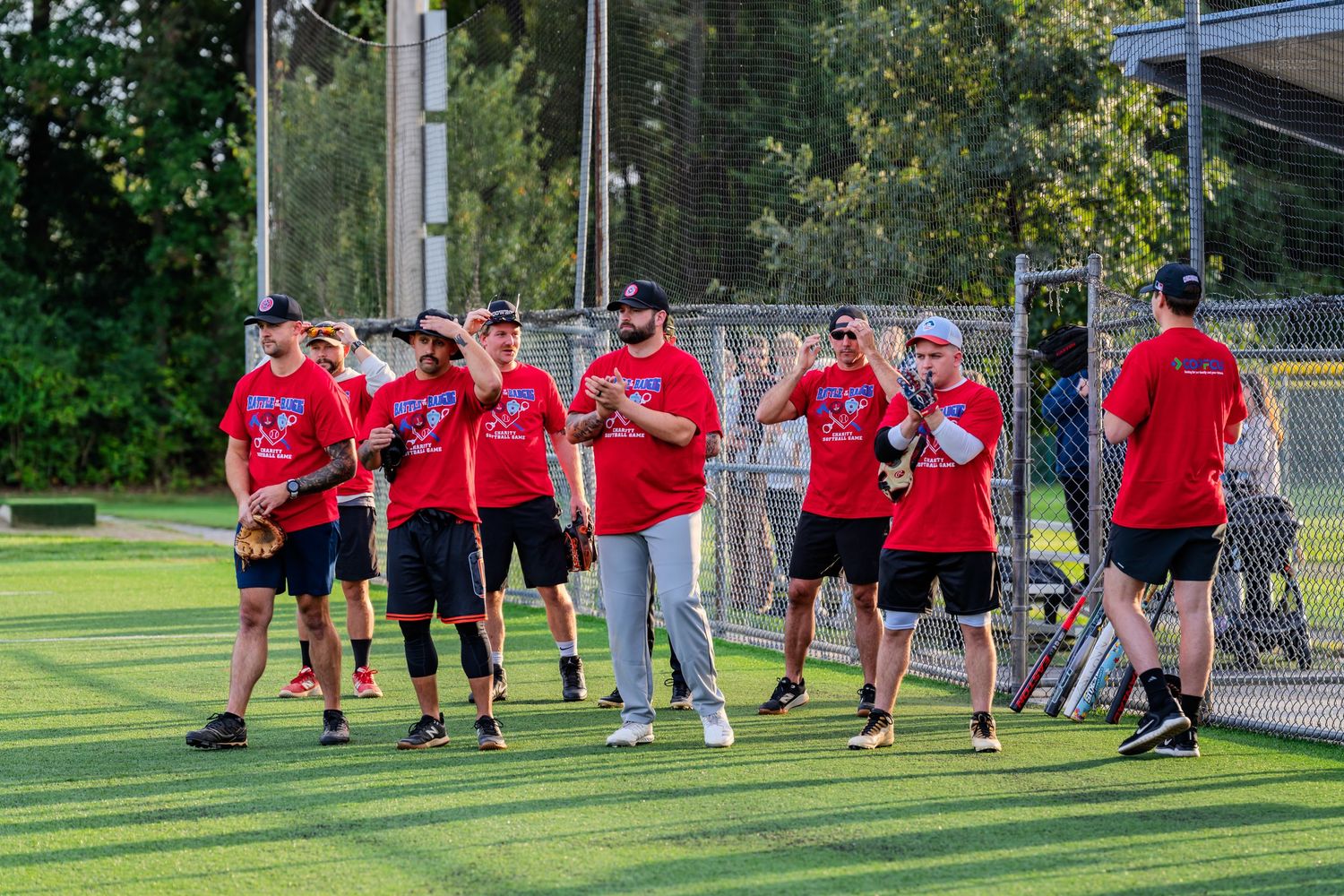A team of softball players in red uniforms gather on a green field during a warm-up session.