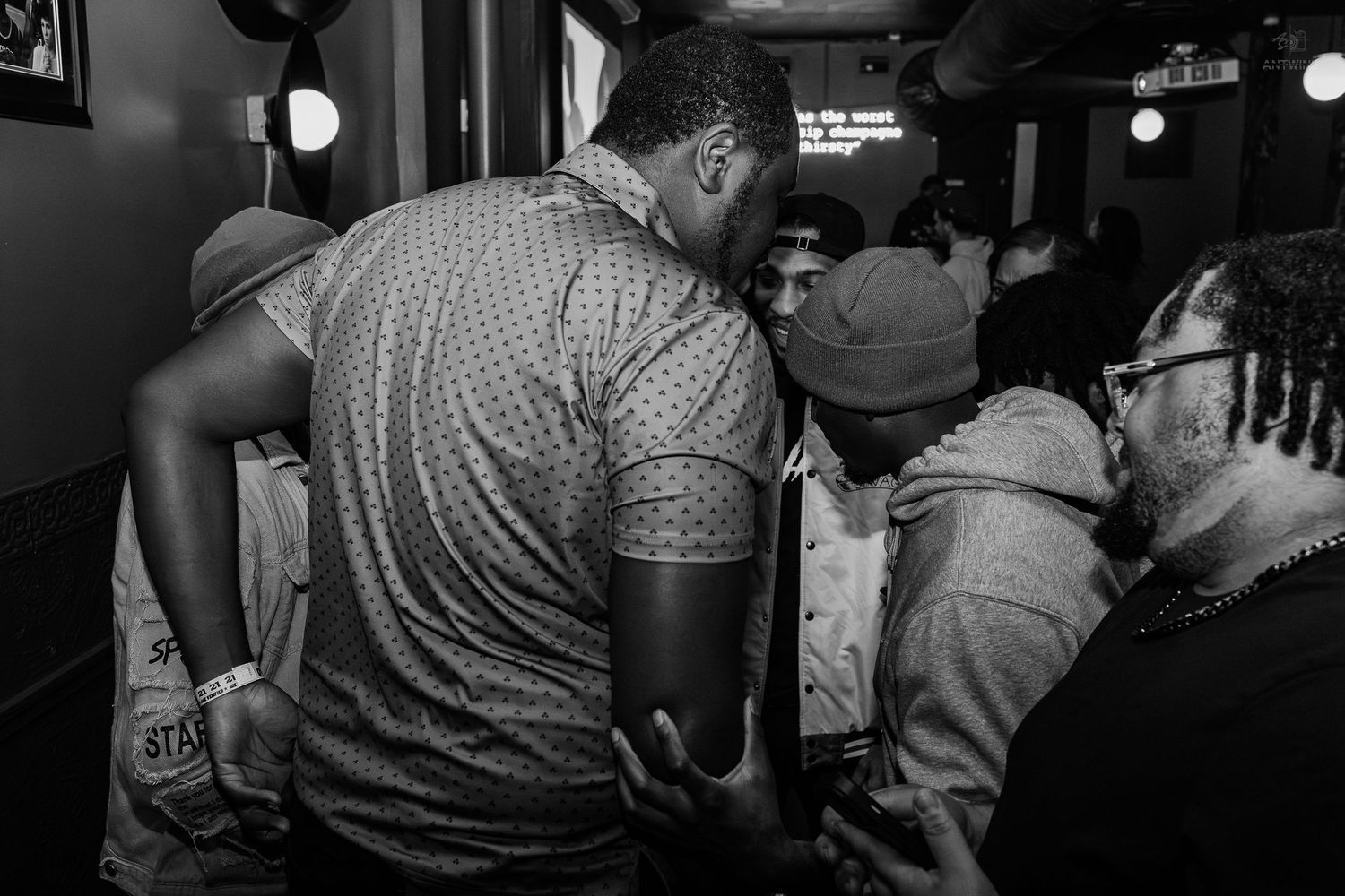 Black and white photo of a crowded indoor gathering with people socializing closely in a dimly lit venue.