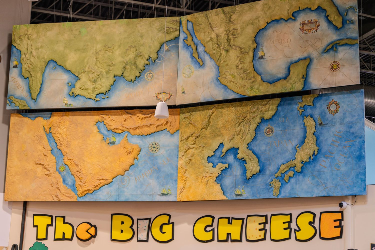 Large painted map mural of Asia and Middle East displayed above a sign reading The Big Cheese.