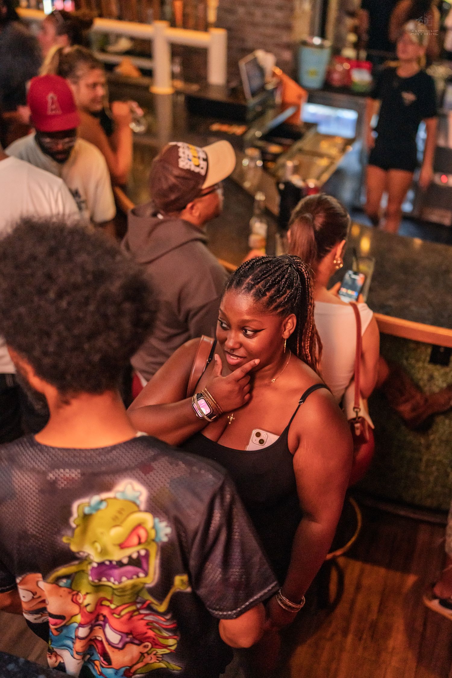 Young woman smiling at the bar of a busy nightclub entertainment venue.