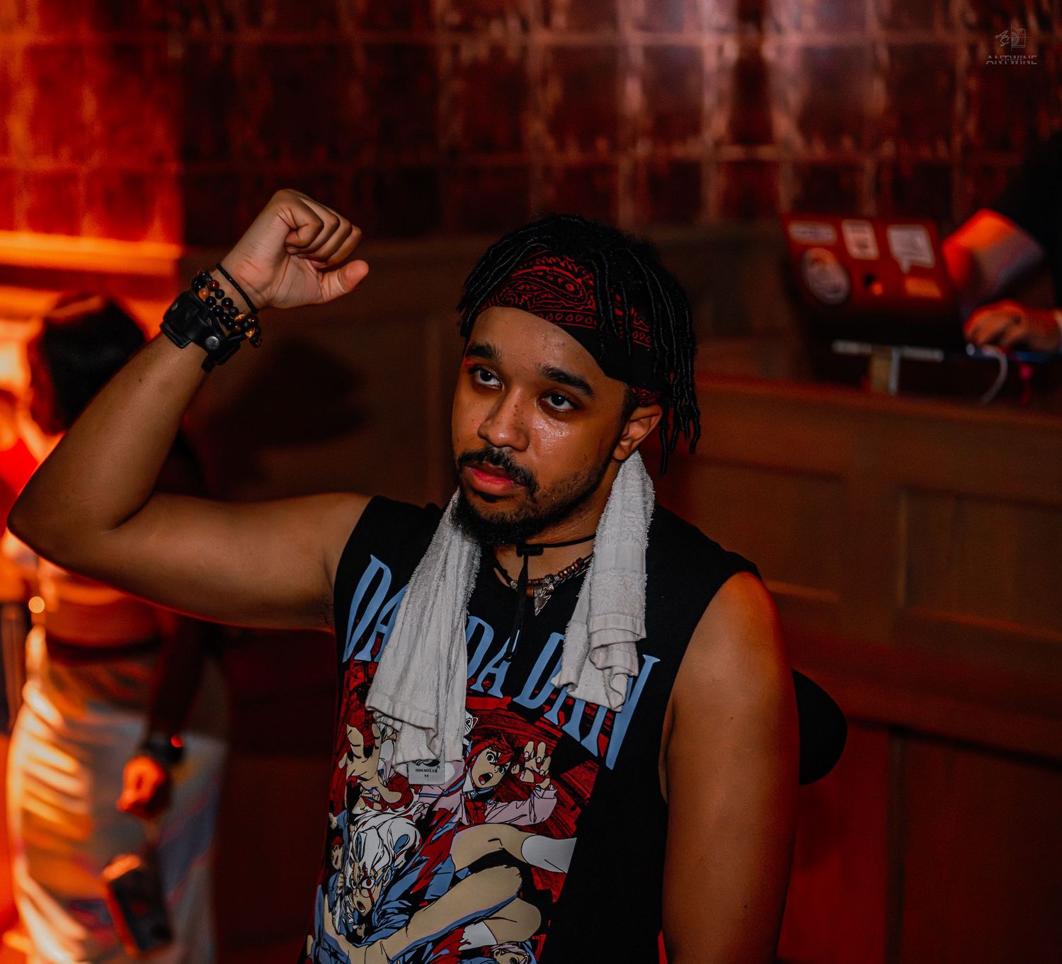 Young man in sleeveless graphic tee raising fist at a nightclub party.