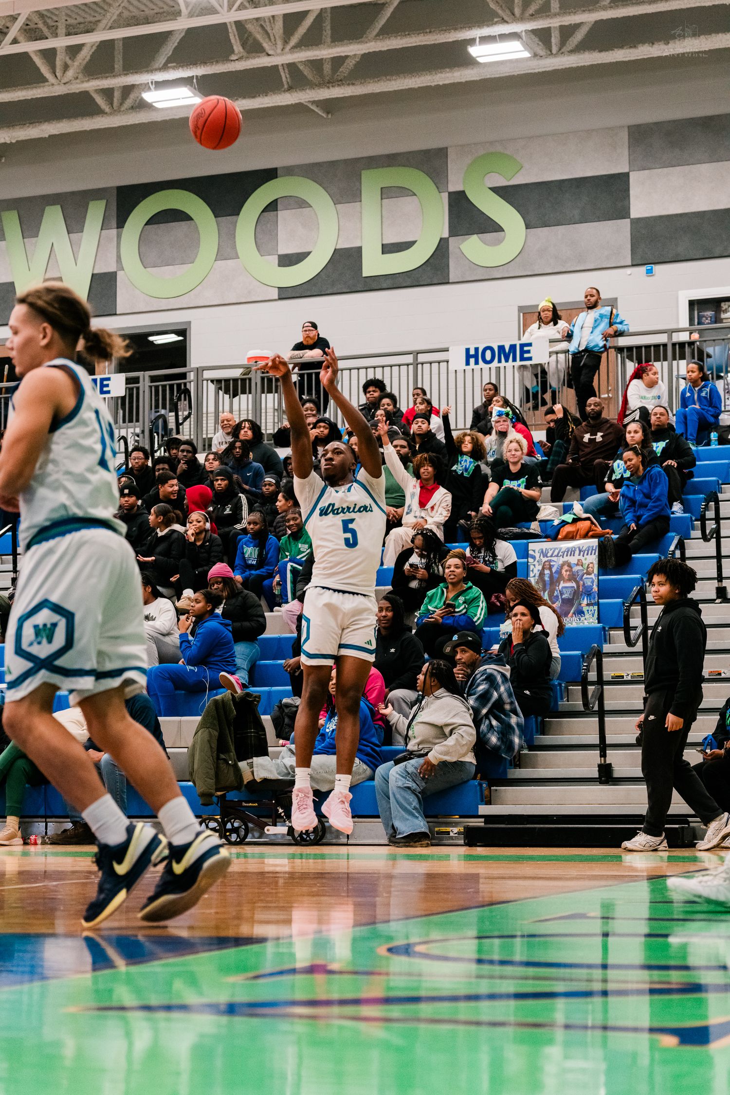 Winton Woods Warriors #5 shoots a jump shot in front of a packed home crowd during a basketball game.