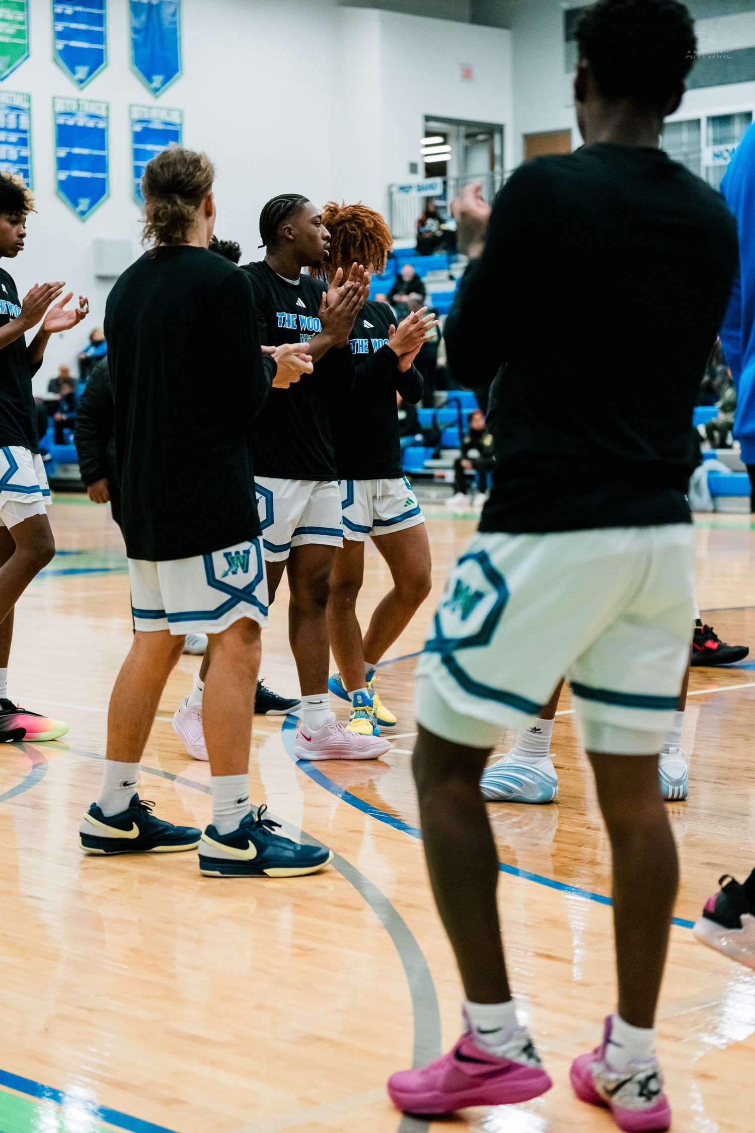 High school basketball team in white uniforms celebrating on court during game.