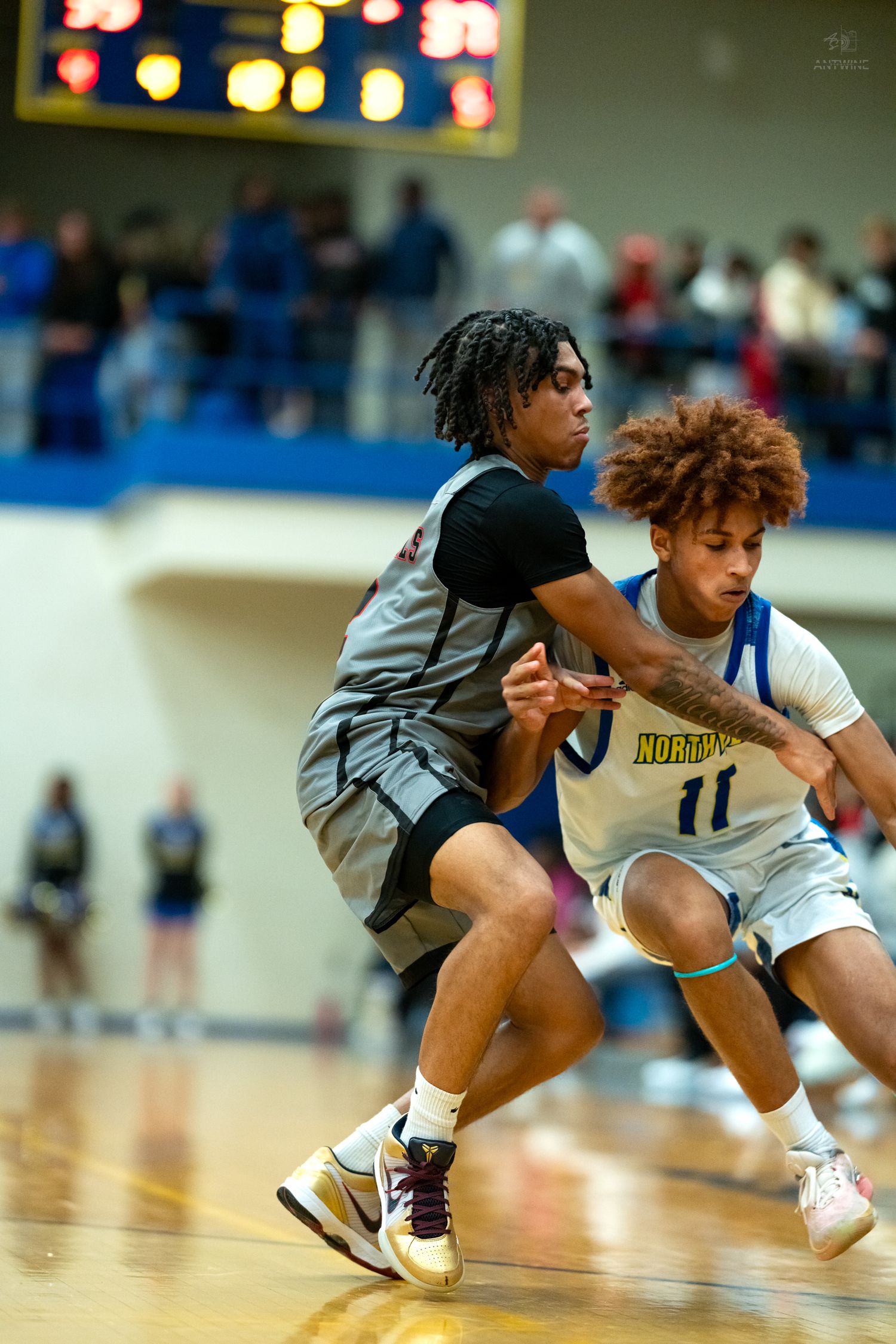 Two high school basketball players battle for position during intense drive to the basket on court.