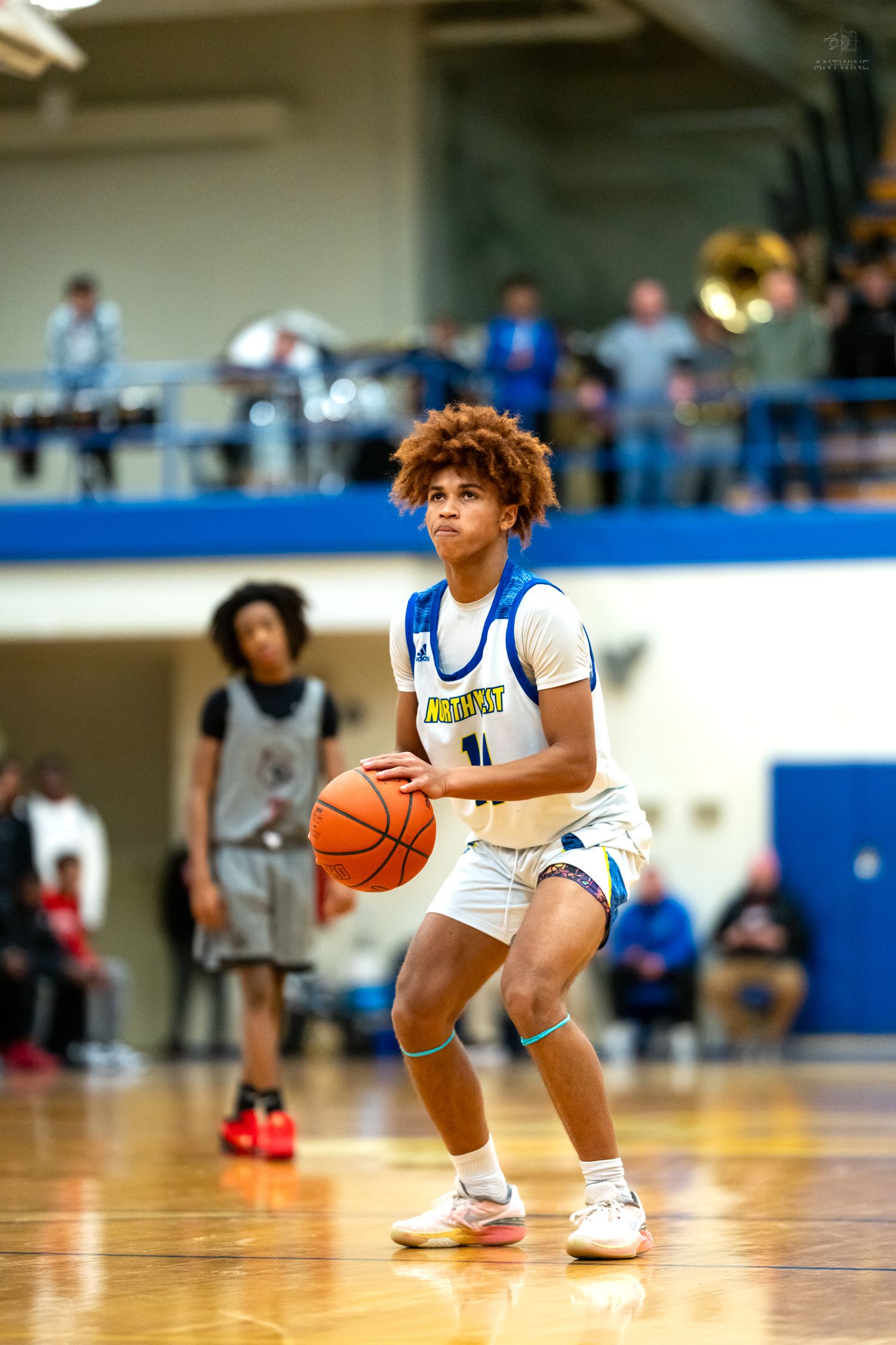 High school basketball player #11 prepares to shoot in blue and white gymnasium.