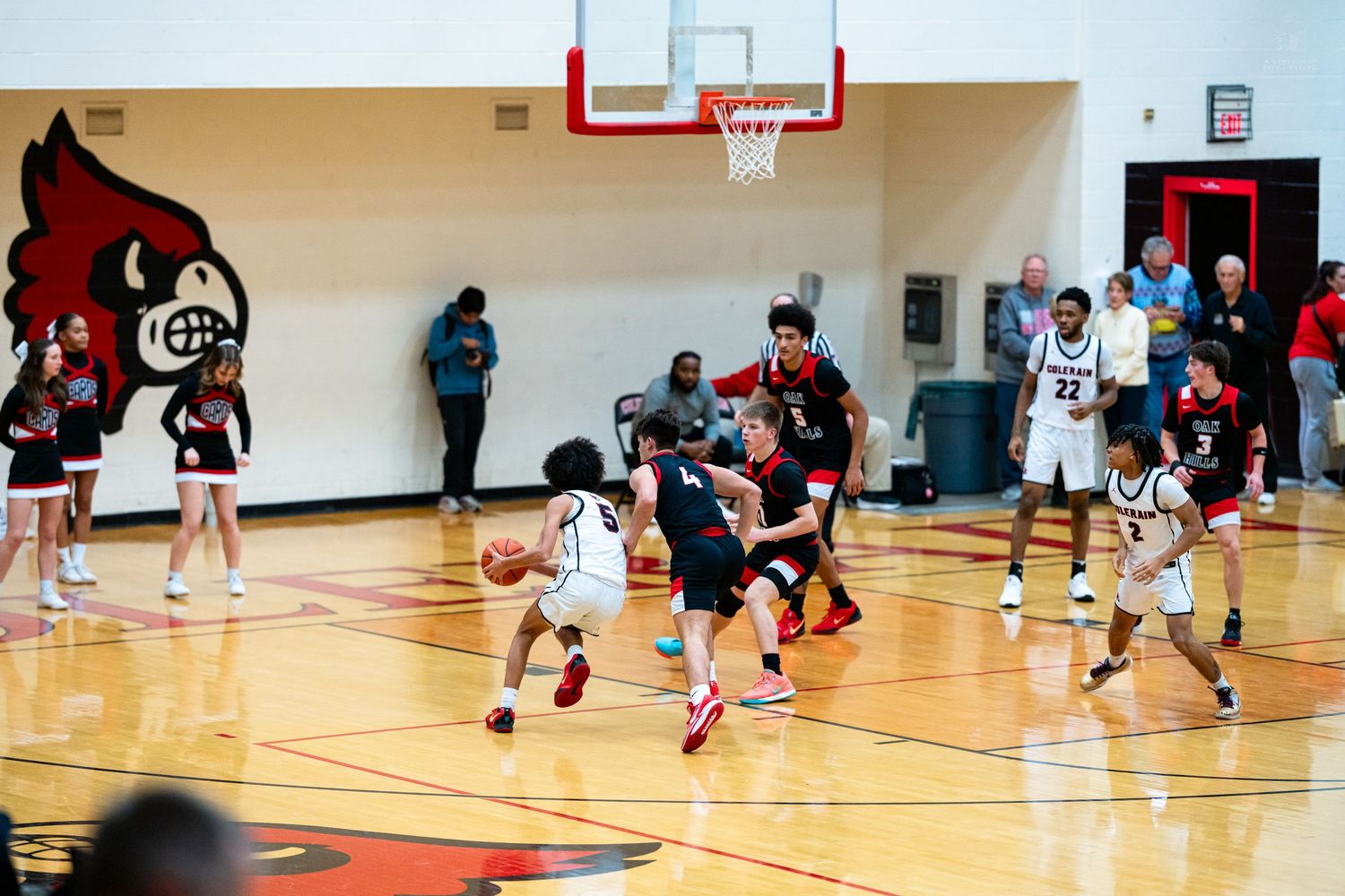 Multiple players battle near basket during fast-paced high school Cardinals basketball game.