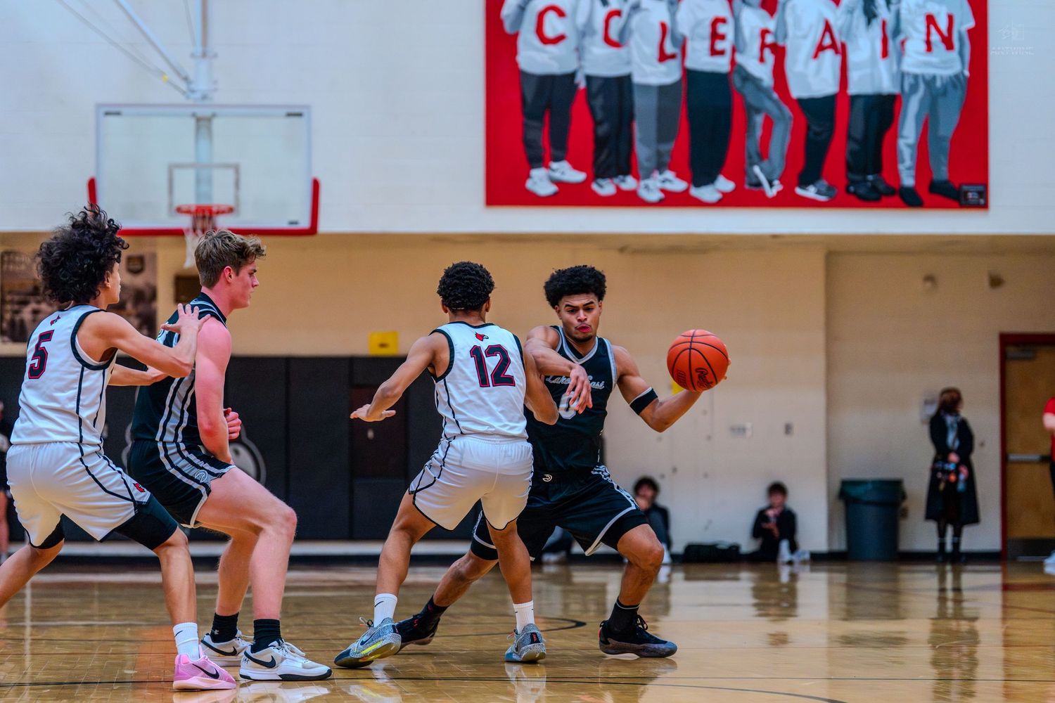 Basketball player drives past multiple defenders under the Colerain gym banner during a high school game.