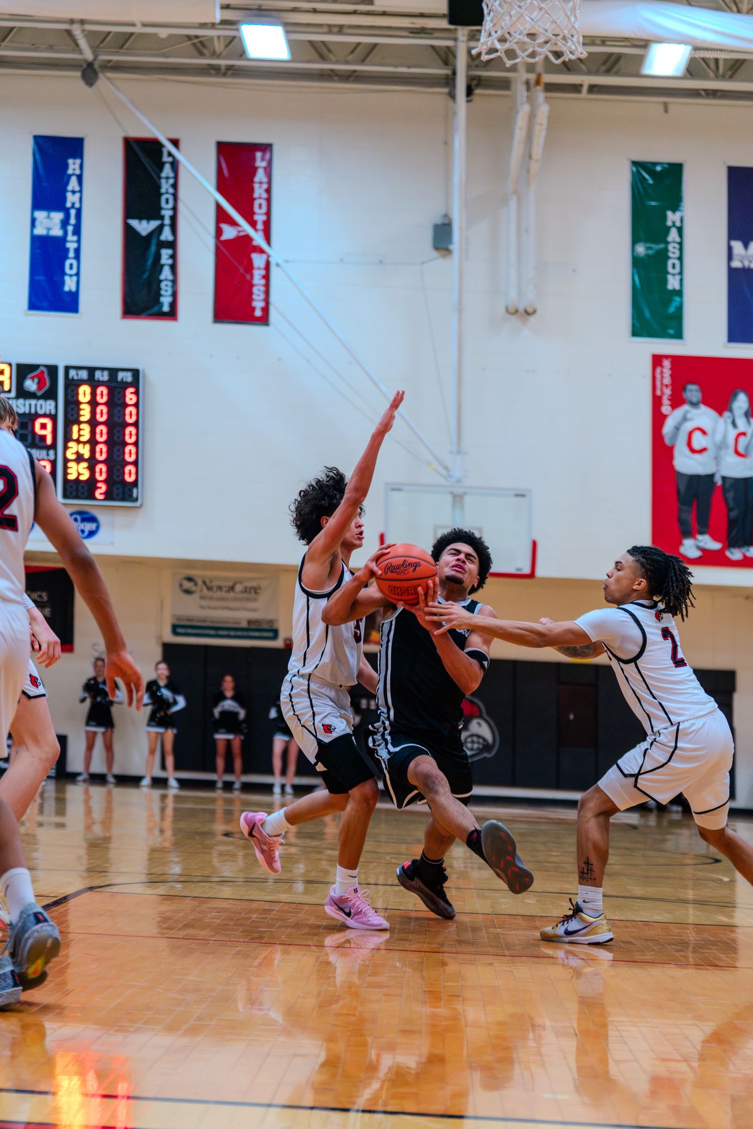 Lakota East player drives to basket through defenders in high school game.