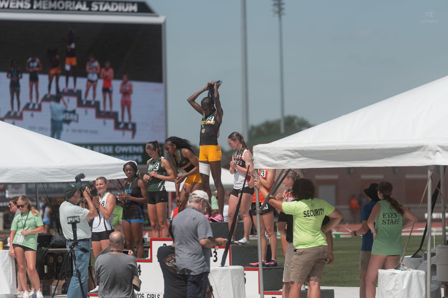 Athletes stand on a podium during an awards ceremony at an outdoor track and field championship.