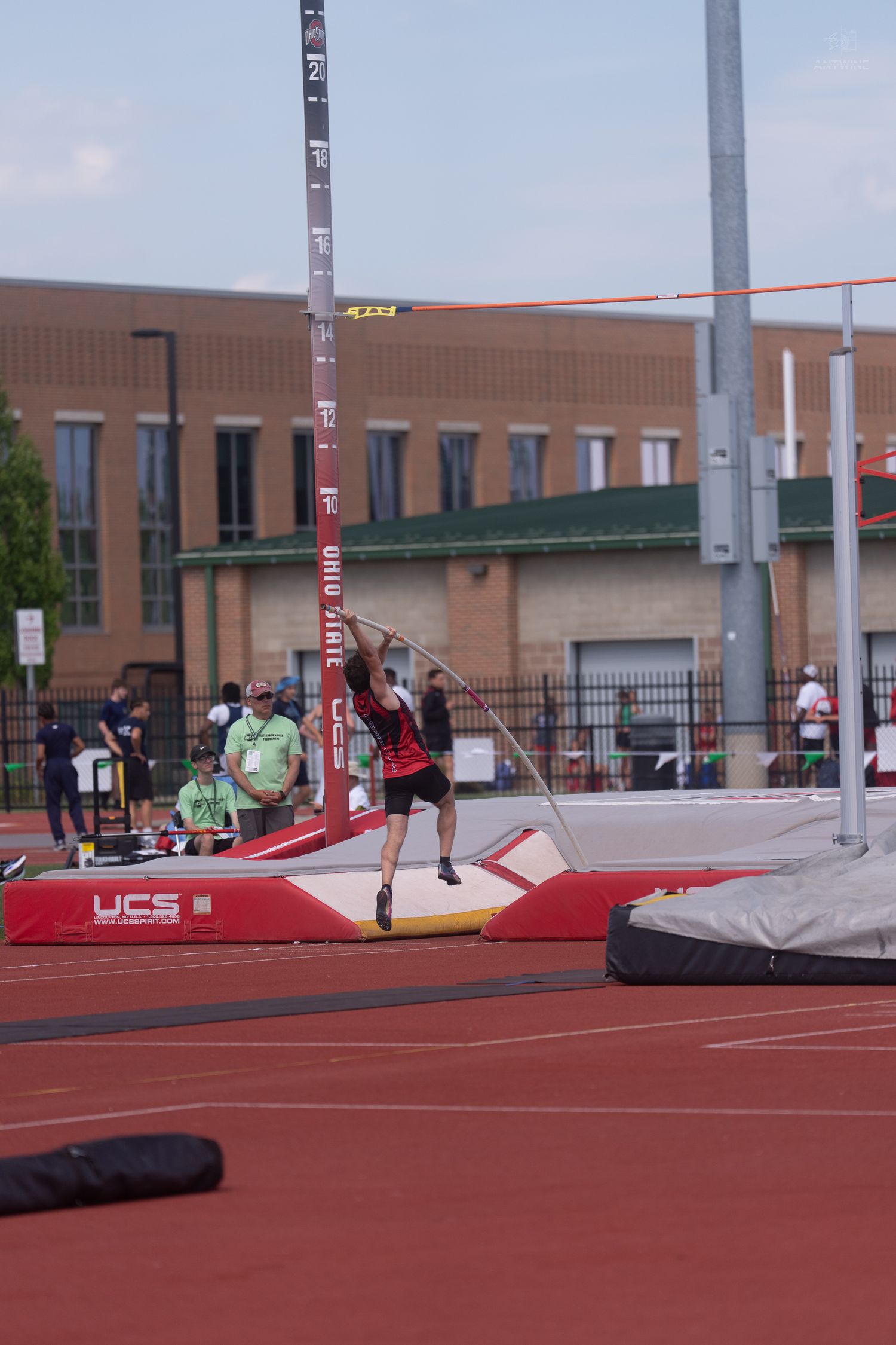 Pole vaulter launches off the mat during a competitive meet at Ohio State track facility.