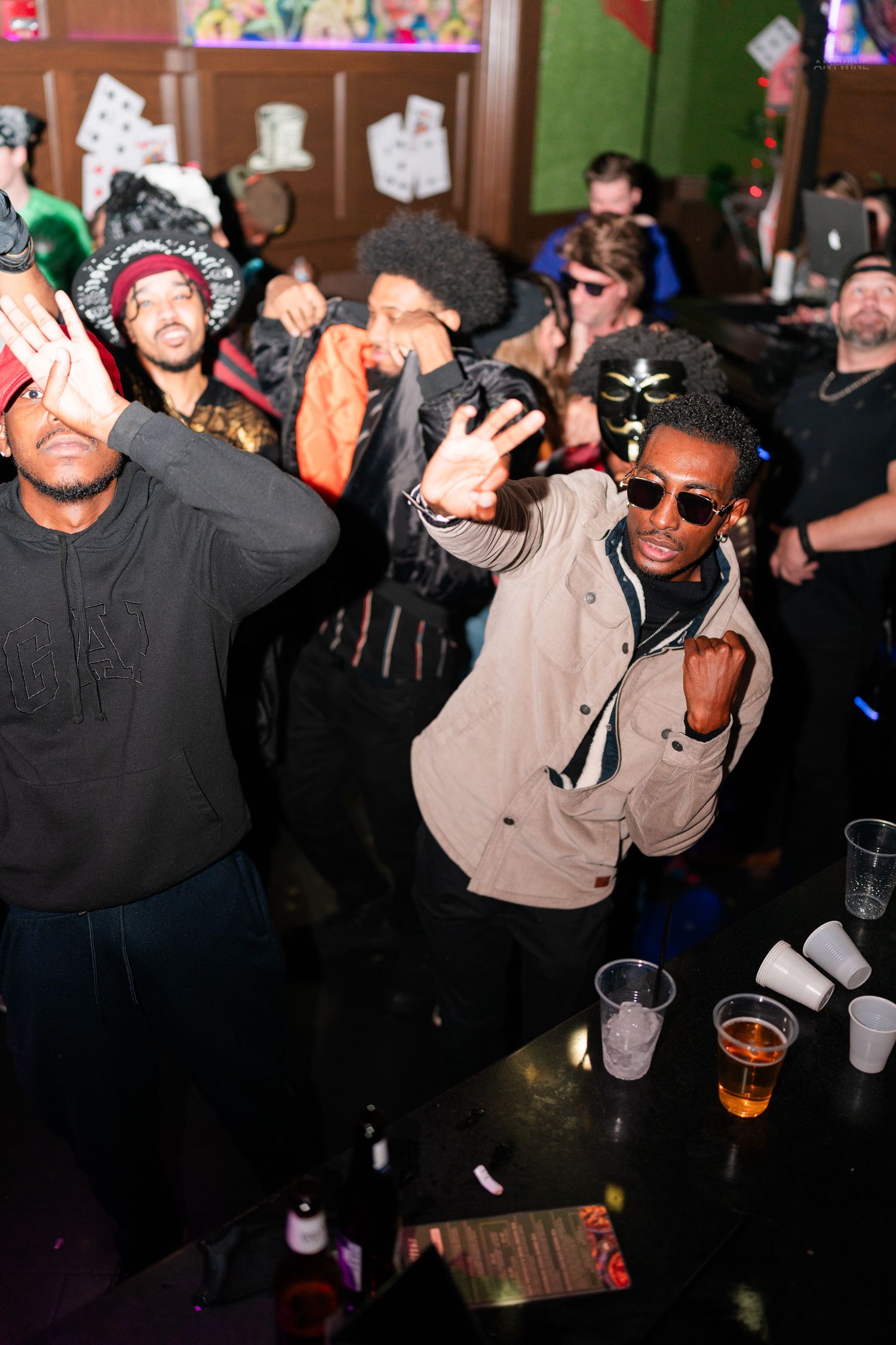 People dancing and celebrating at a lively Halloween party in a bar with drinks on the counter.