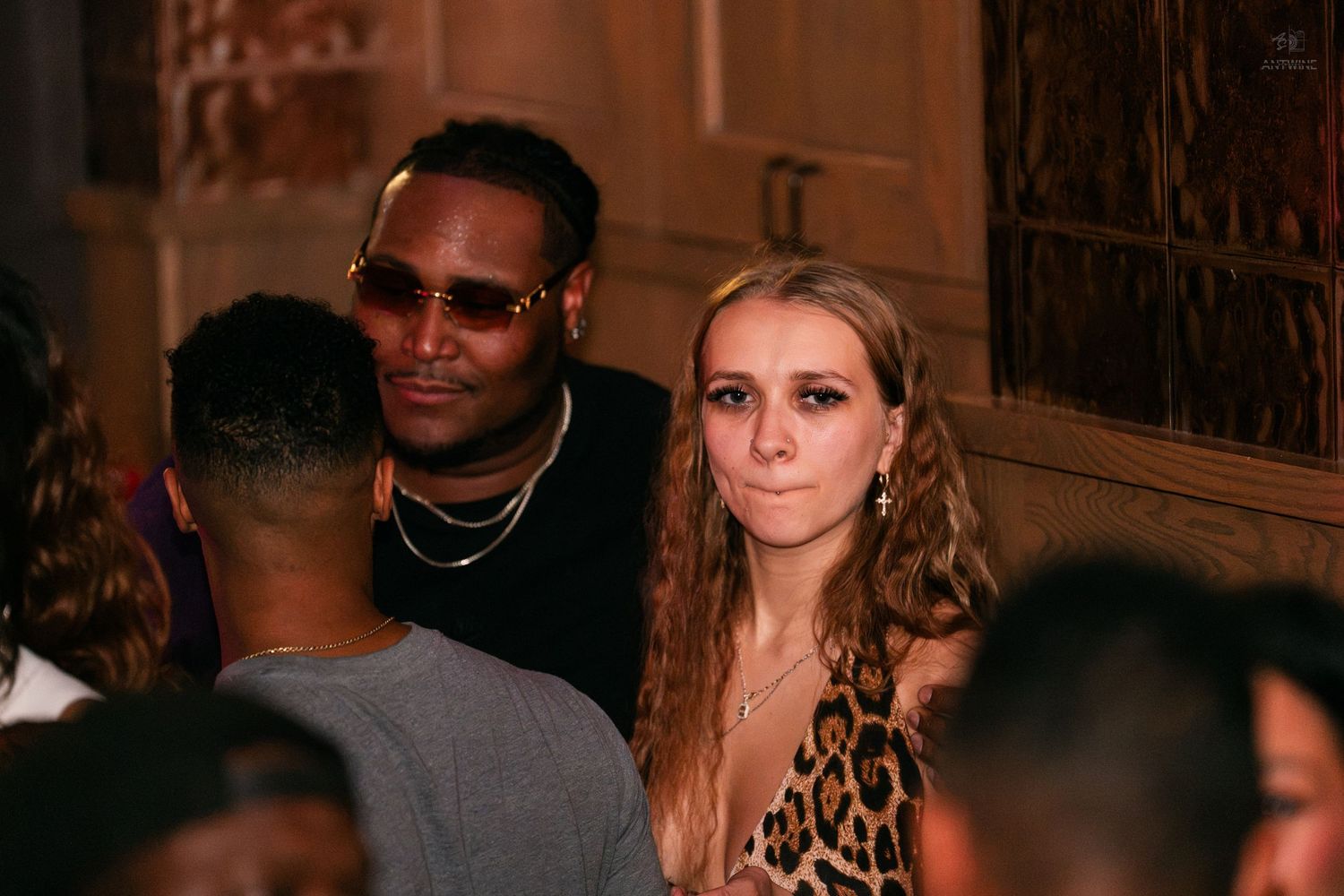 Man and woman posing together at a dimly lit nightclub or bar event.