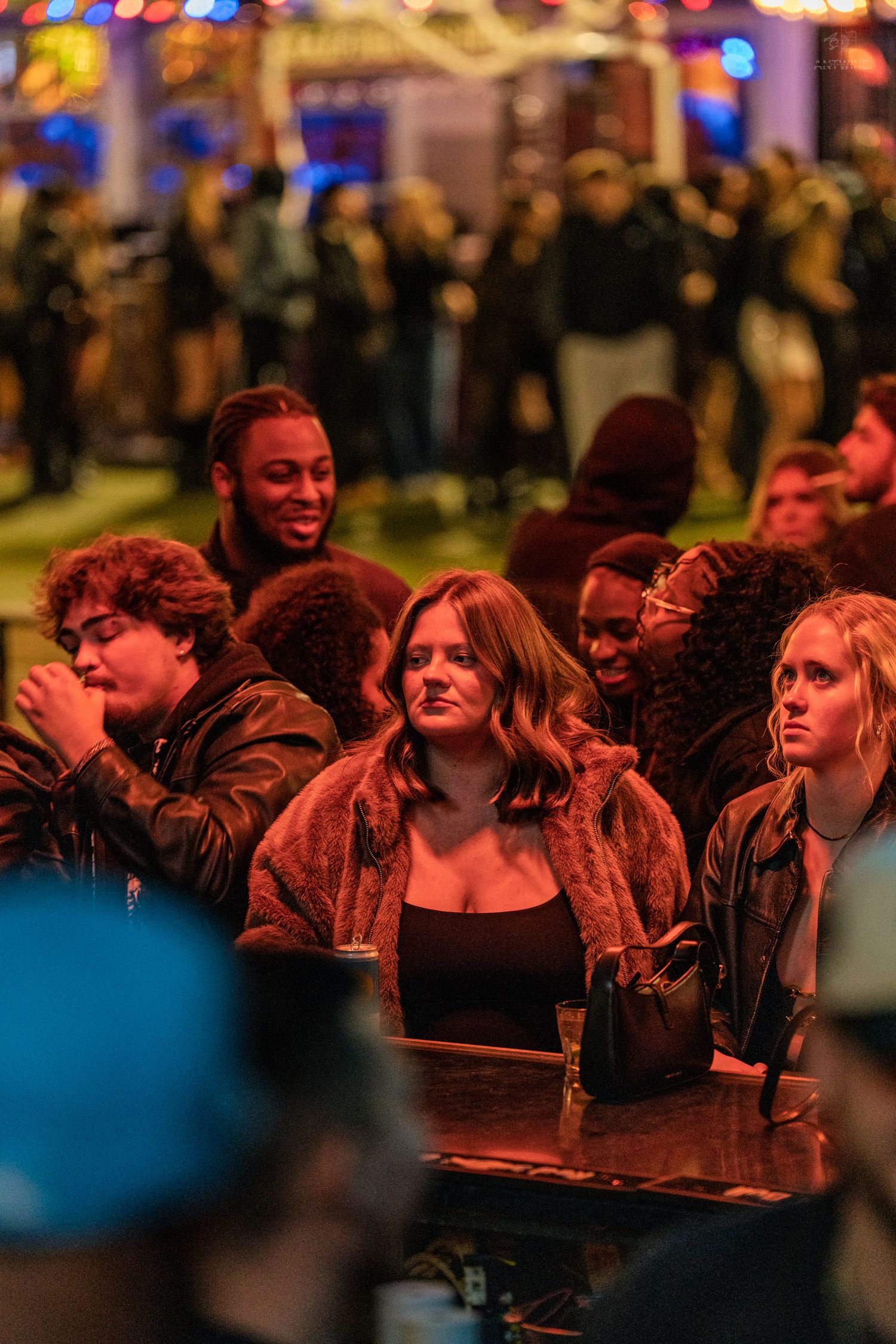 Group of young people seated at an outdoor evening event with warm orange lighting.