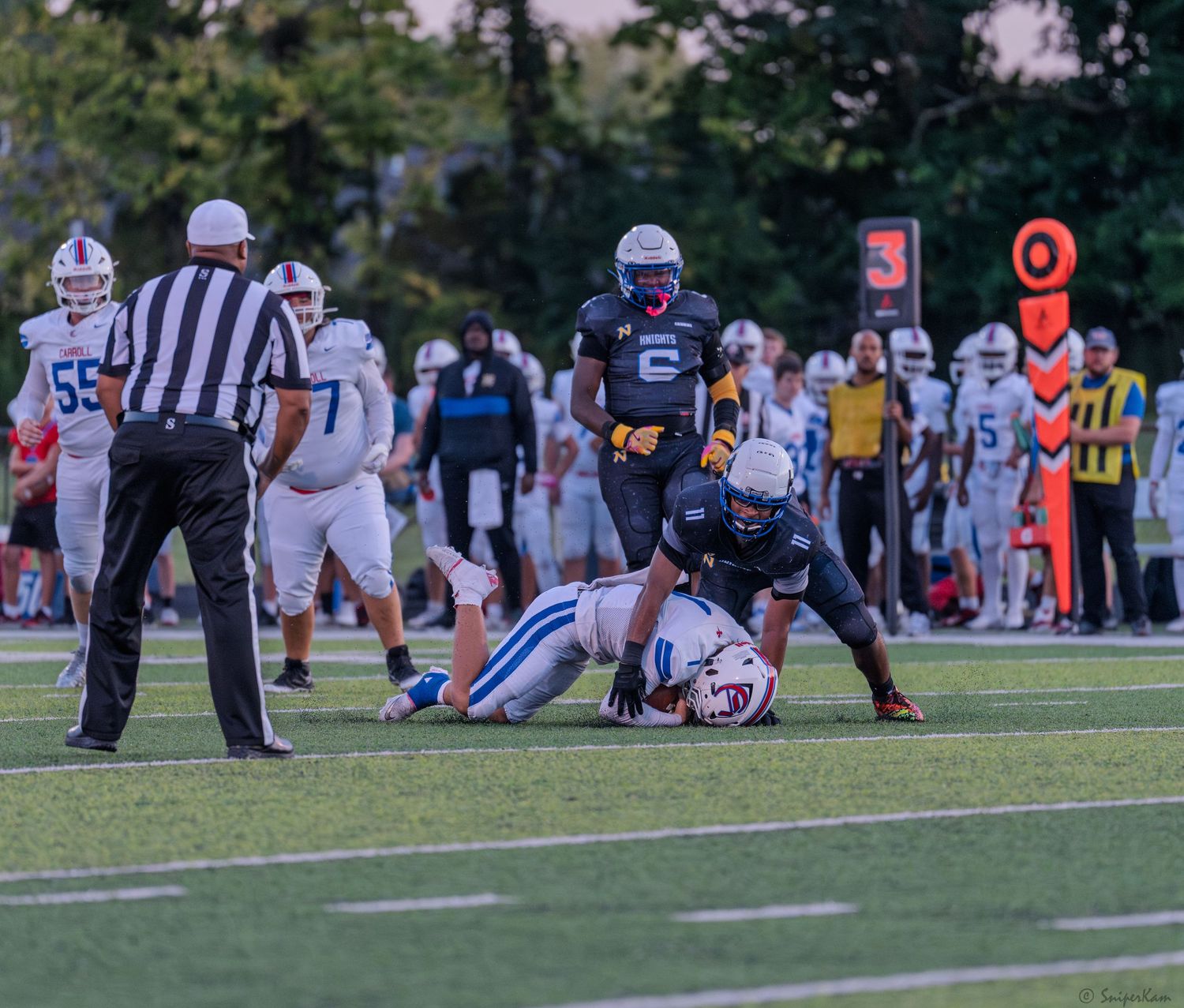 Referee watches as a football player tackles an opponent during a competitive game.