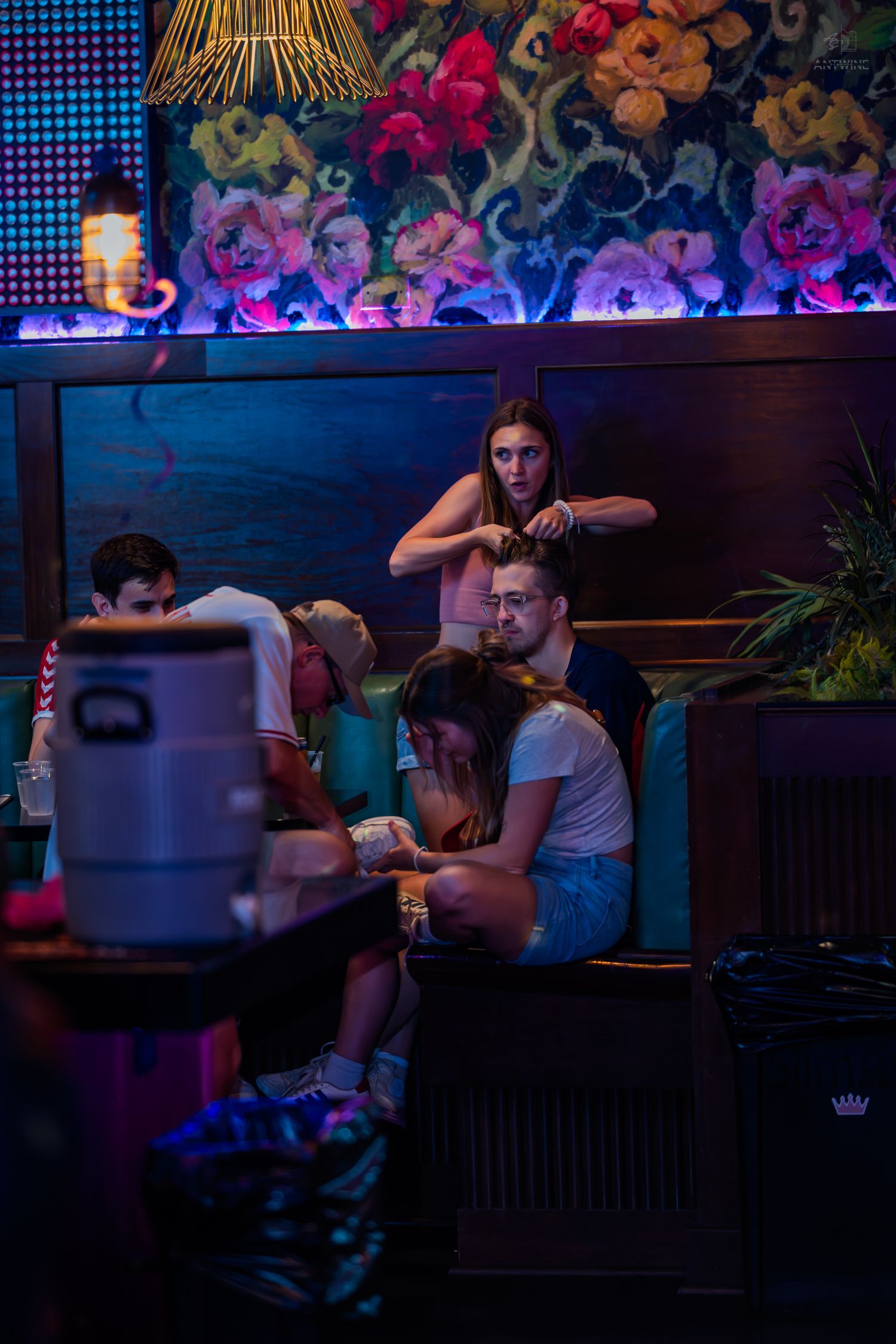Group of young people relaxing in a colorful booth at a vibrant nightclub.