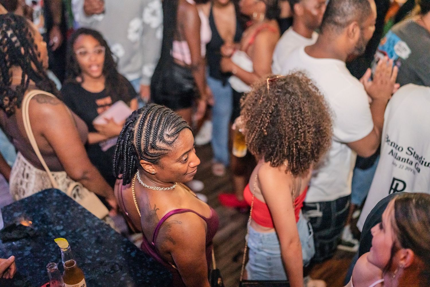 Young women with braided hairstyles enjoying a vibrant nightclub party together.
