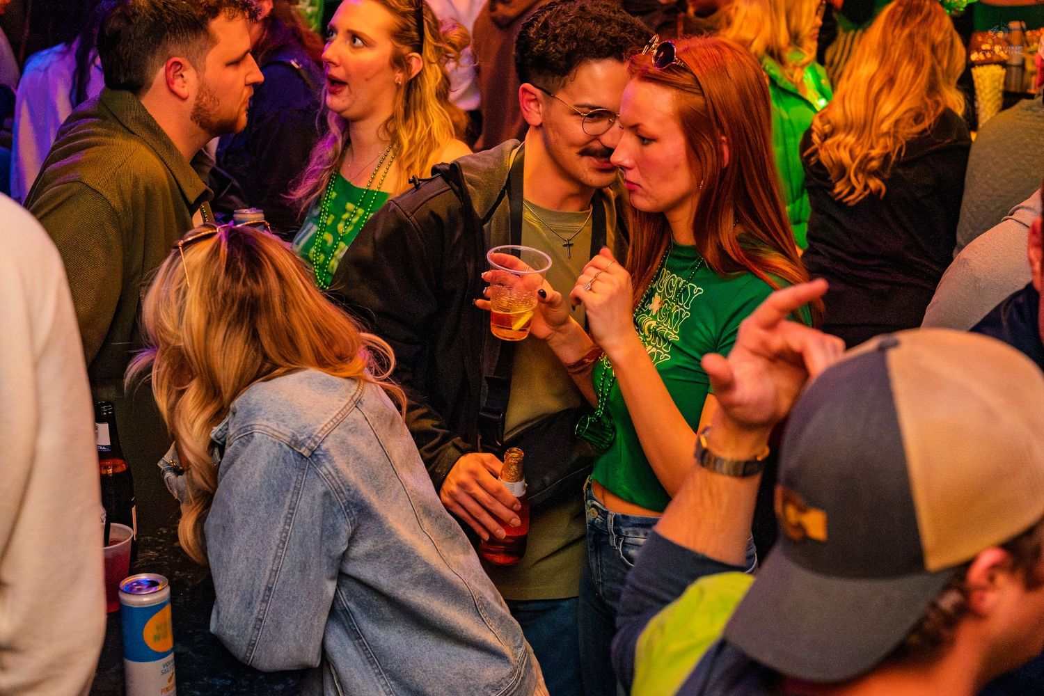 Young couple drinking and socializing at a festive St. Patrick's Day bar party.