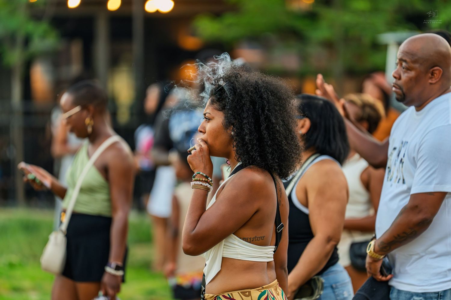 Woman with curly hair at an outdoor Juneteenth celebration surrounded by a diverse crowd.