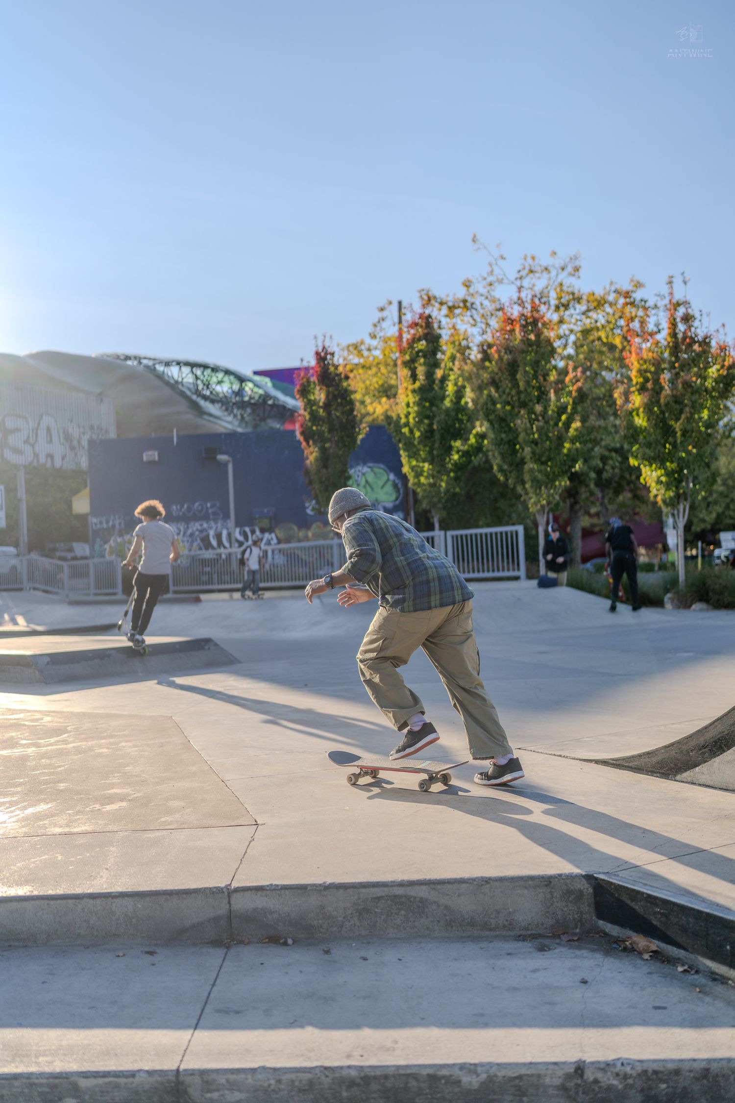 Skateboarder performing tricks at an outdoor skate park on a sunny day.
