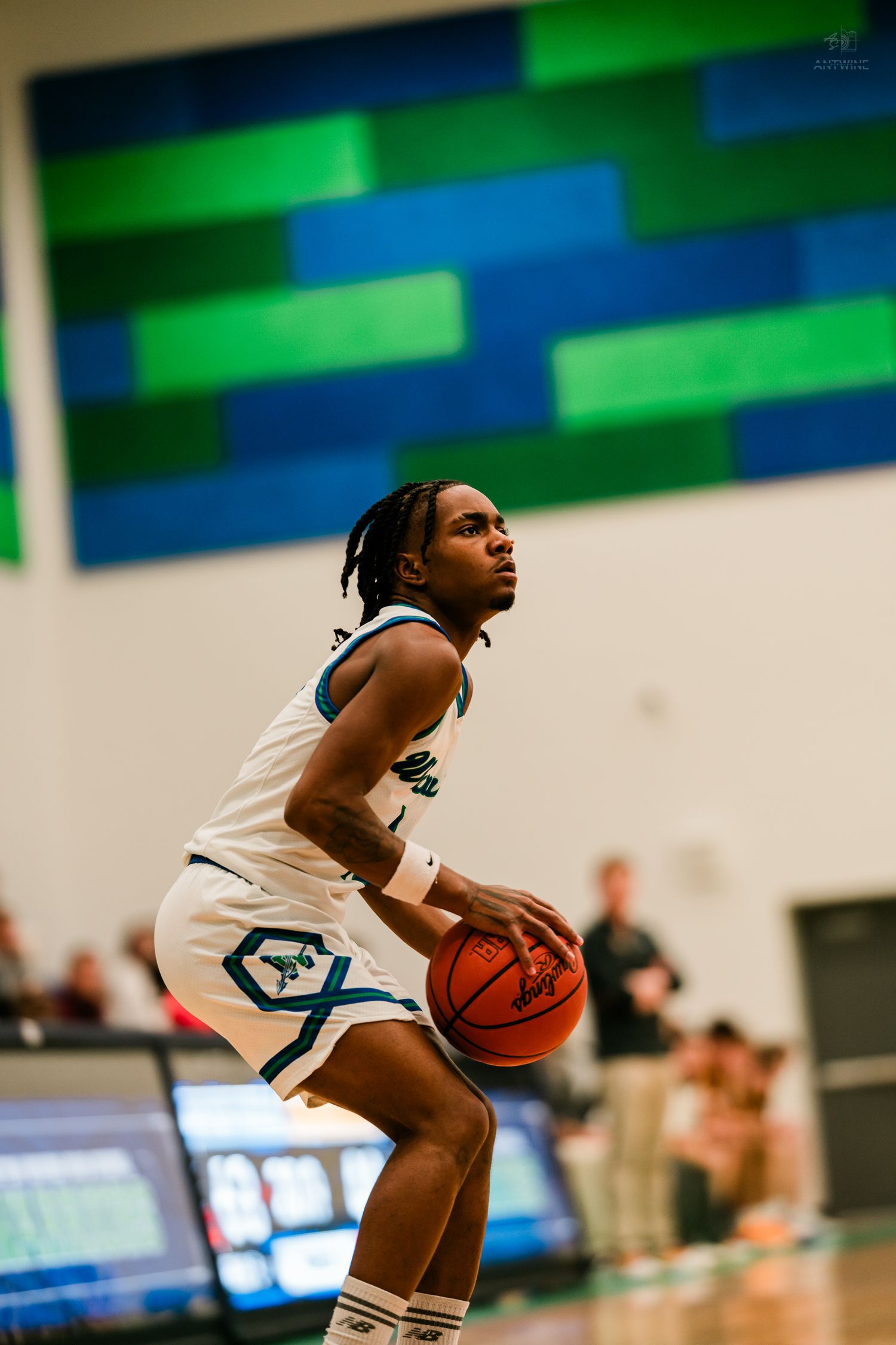 A Warriors basketball player prepares to shoot a free throw during an indoor high school basketball game.
