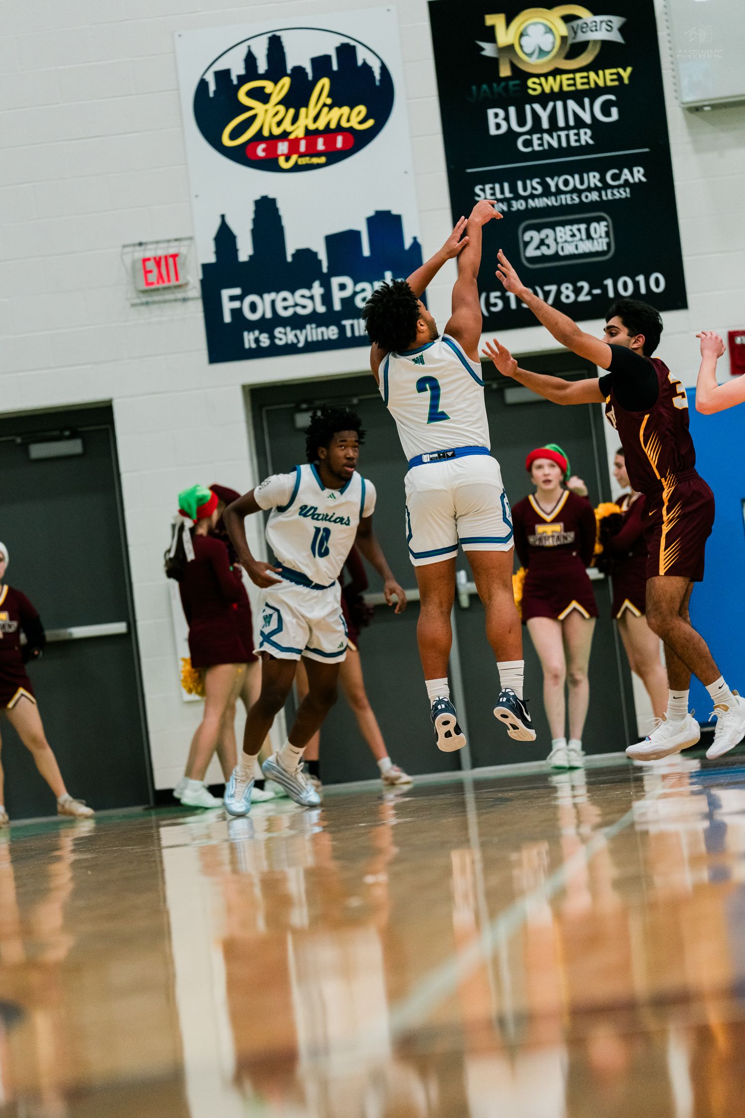 Warriors player #2 attempts a jump shot over defenders during a high school basketball game at Forest Park.