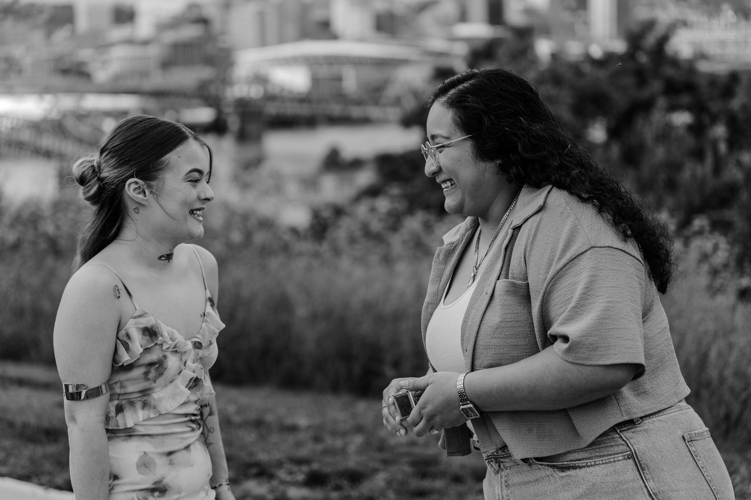 Two women sharing a joyful moment outdoors in black and white photography.