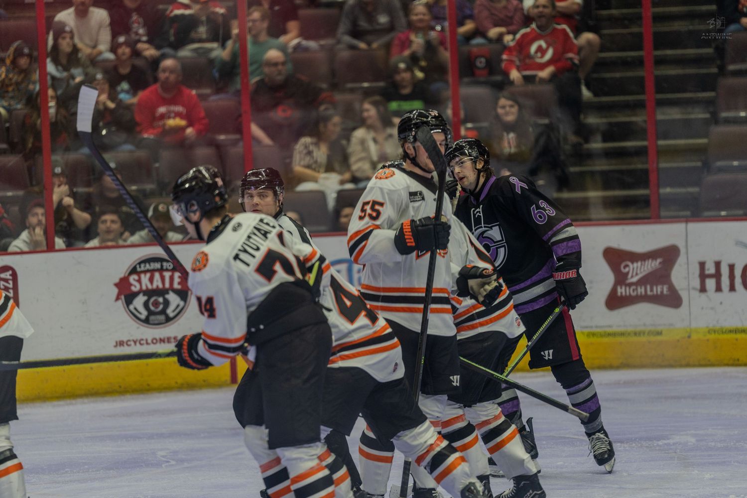 Hockey players battle in front of the net during a physical minor league ice hockey game on home ice.