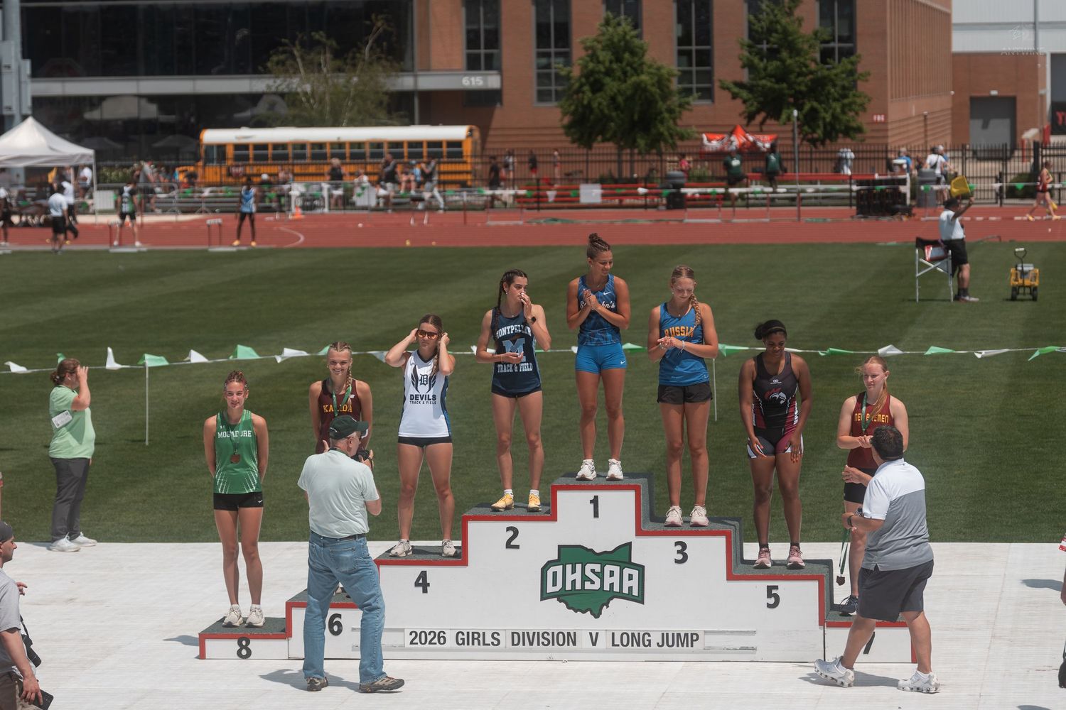 Girls stand on an OHSAA Division V Long Jump awards podium at a high school track and field championship.