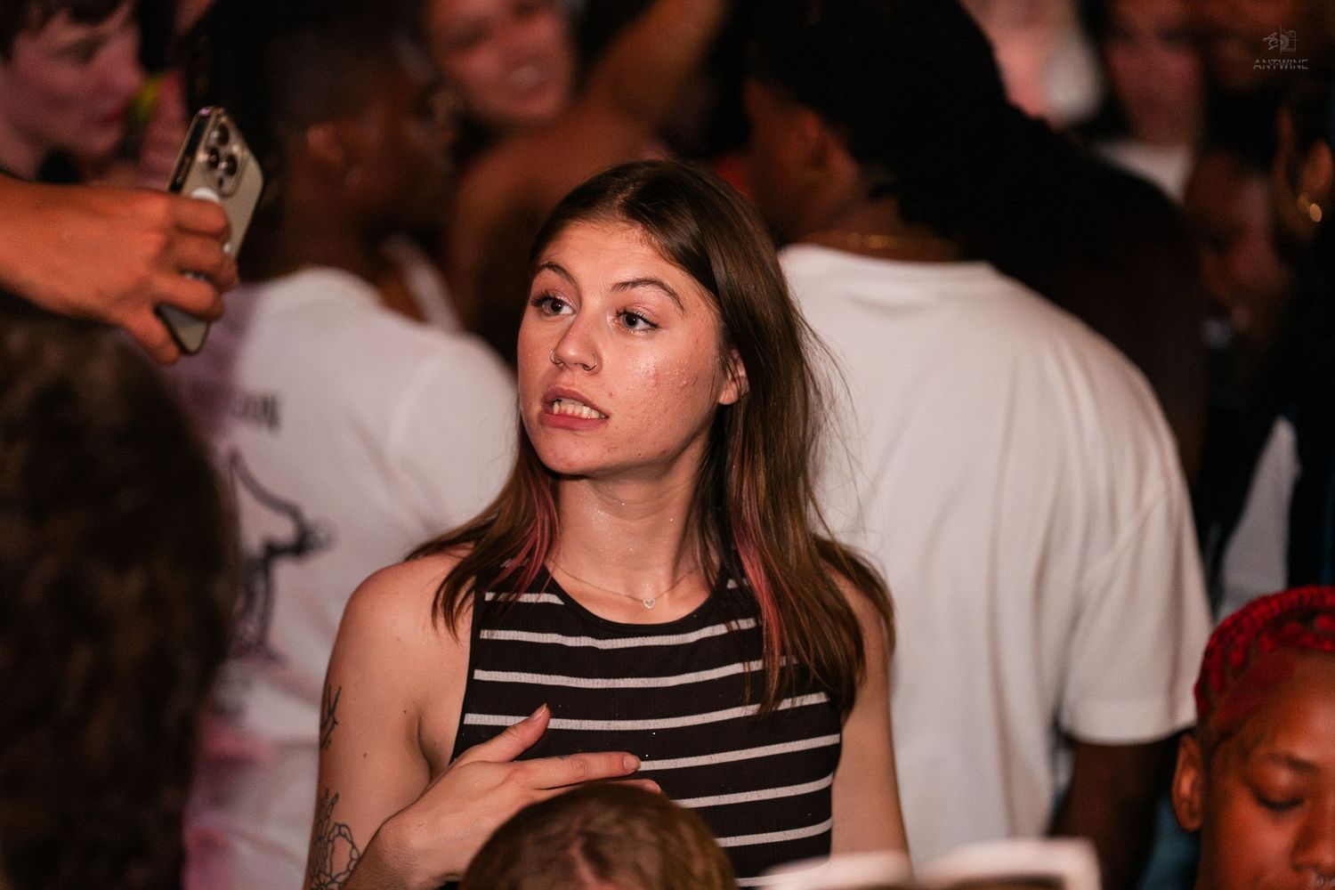 Young woman in striped top looking up in a crowded party venue.