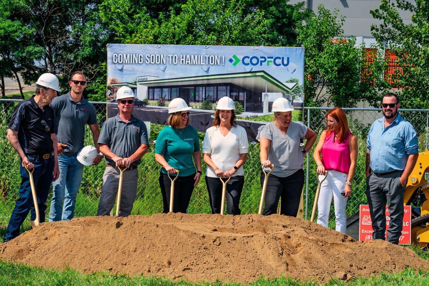 Seven people wearing hard hats hold shovels at COPFCU new Hamilton location groundbreaking ceremony.