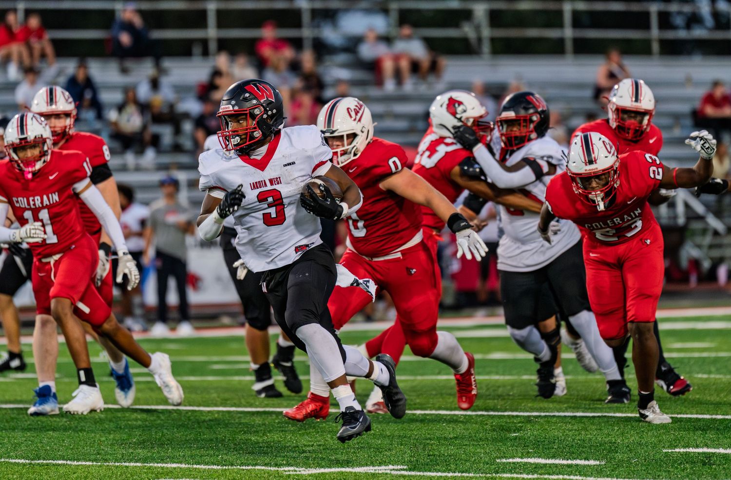 A football player in a dark uniform runs with the ball during a high school game against Colerain.