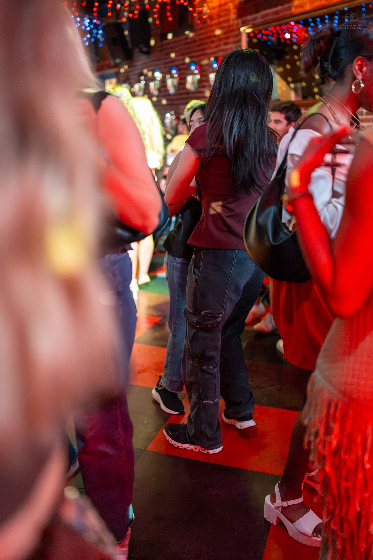 People dancing and socializing at a vibrant nightclub event with colorful lights.