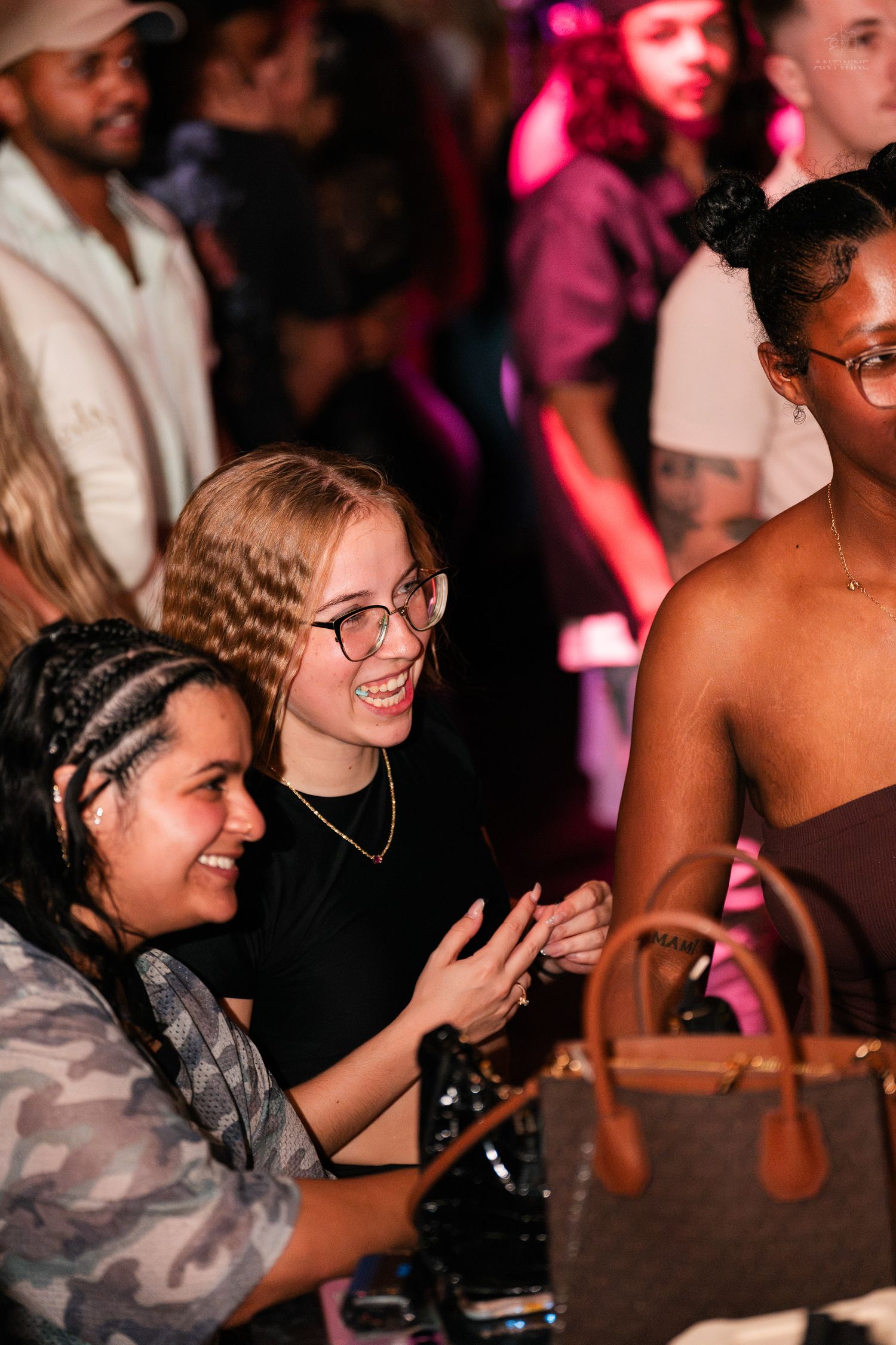 Group of smiling women socializing at a crowded nightclub event.