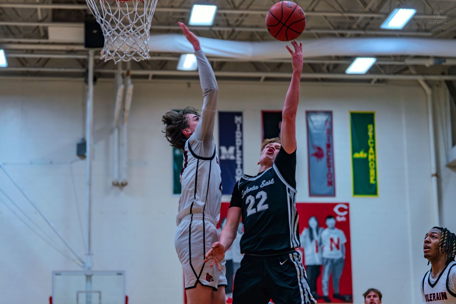 Player number 22 attempts a layup while being blocked during a high school basketball game.