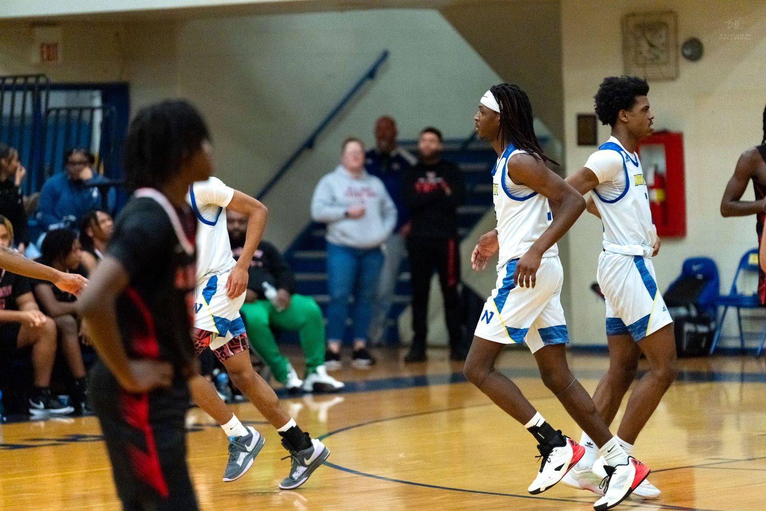 High school basketball players in blue and white uniforms run down the court during an intense game.