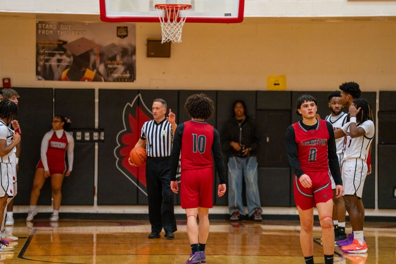 High school basketball players line up for a free throw attempt as a referee observes during a game.